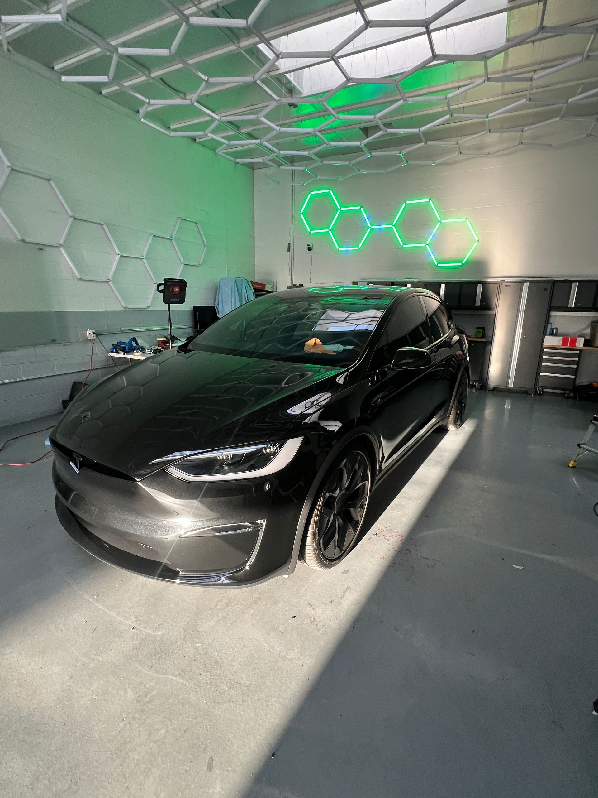 Black Tesla in a modern garage with green hexagon wall lights