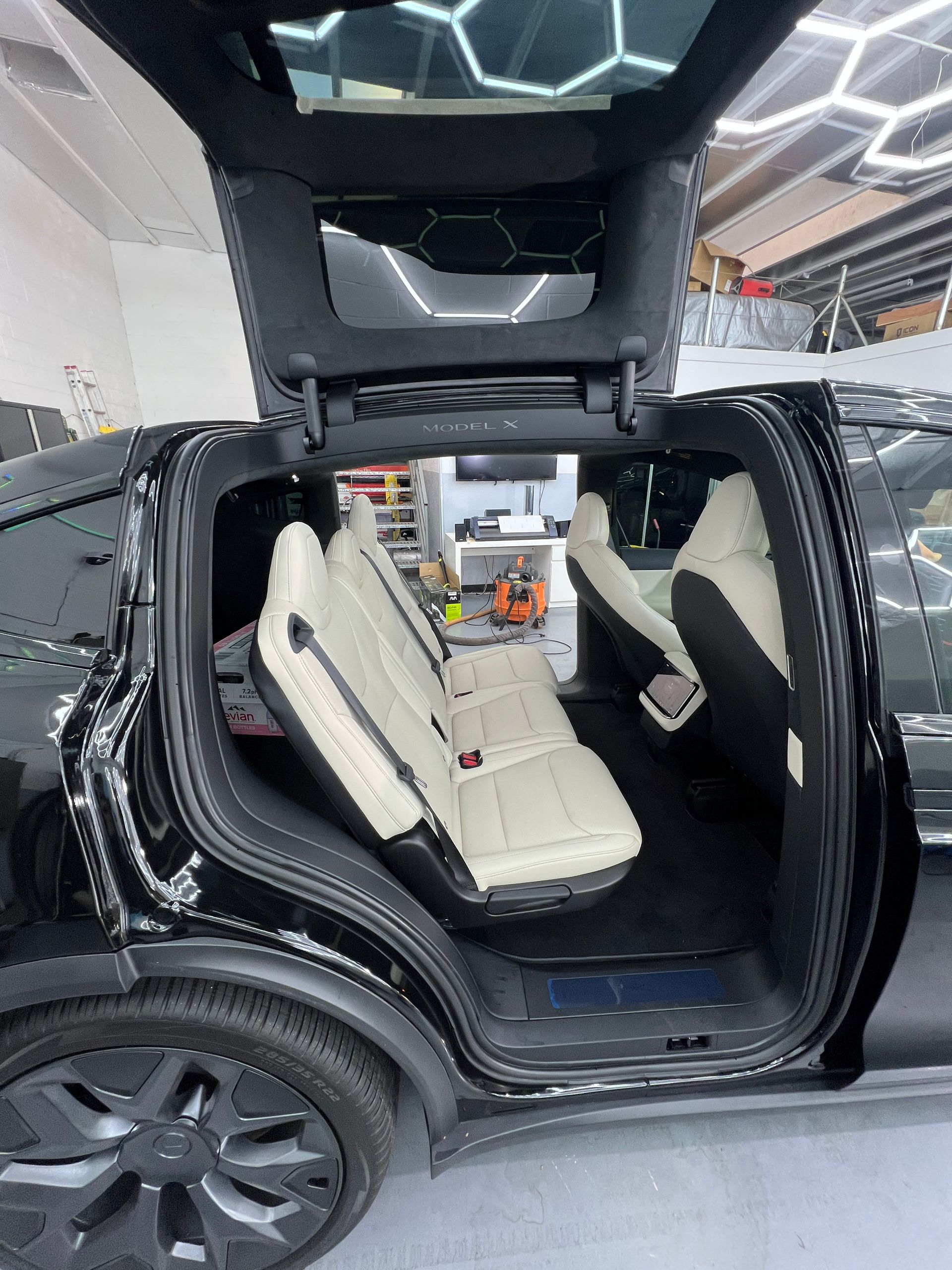 Black SUV with gullwing doors open, showing a white interior in a showroom.