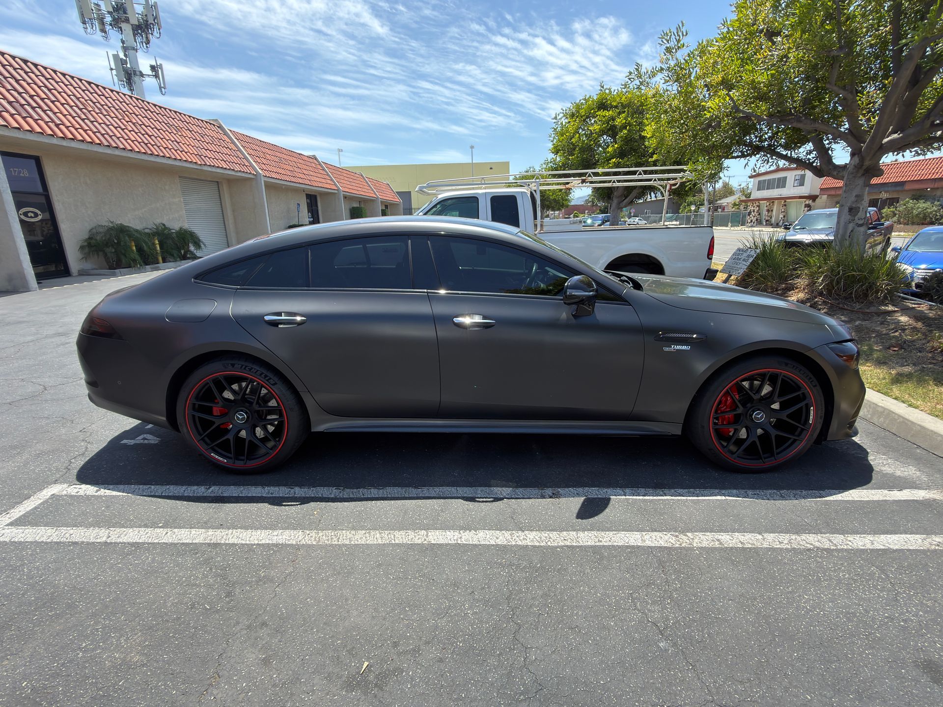 Matte black sports sedan parked in a lot under bright sunlight, side view
