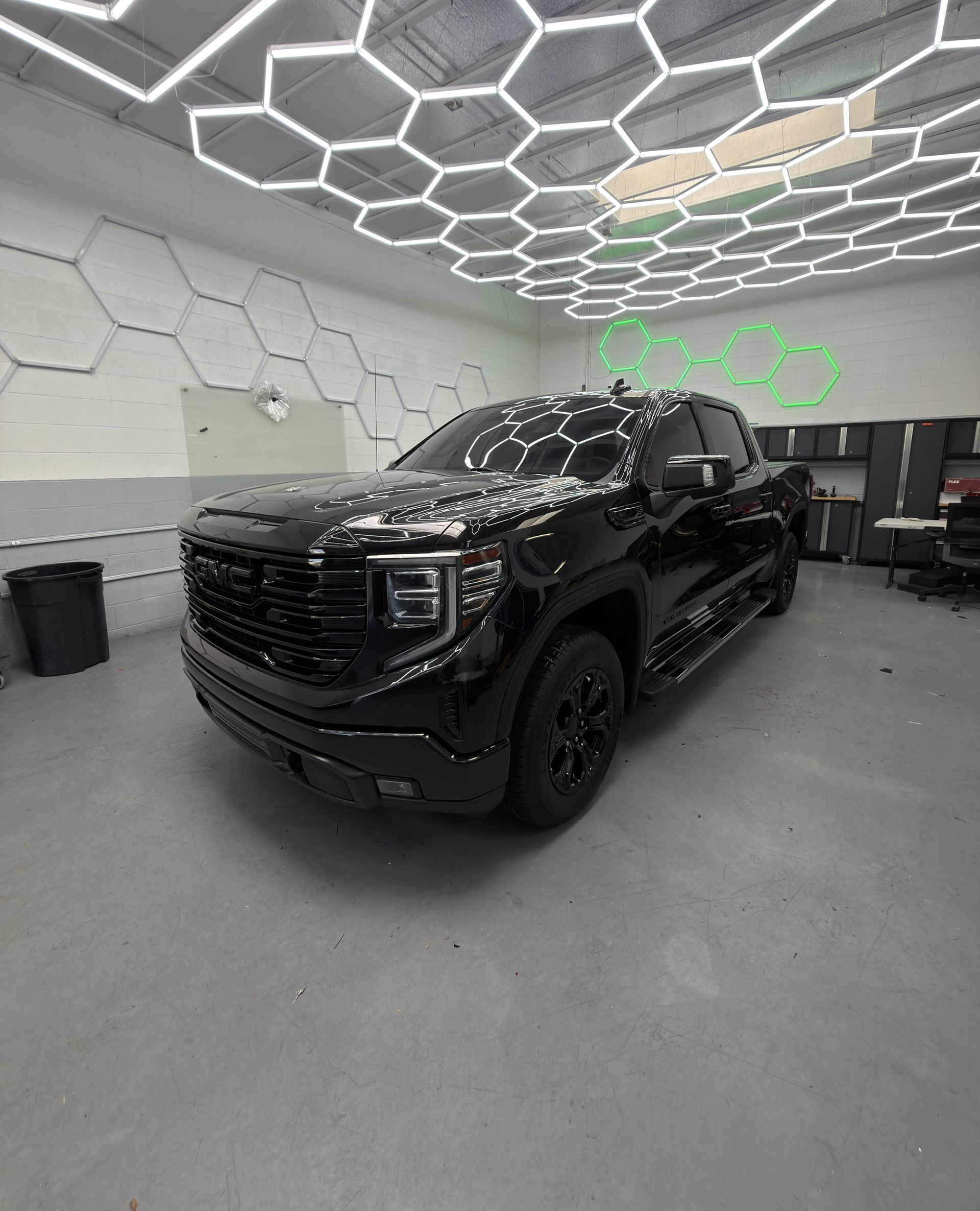 Black pickup truck parked in a modern garage with hexagonal ceiling lights