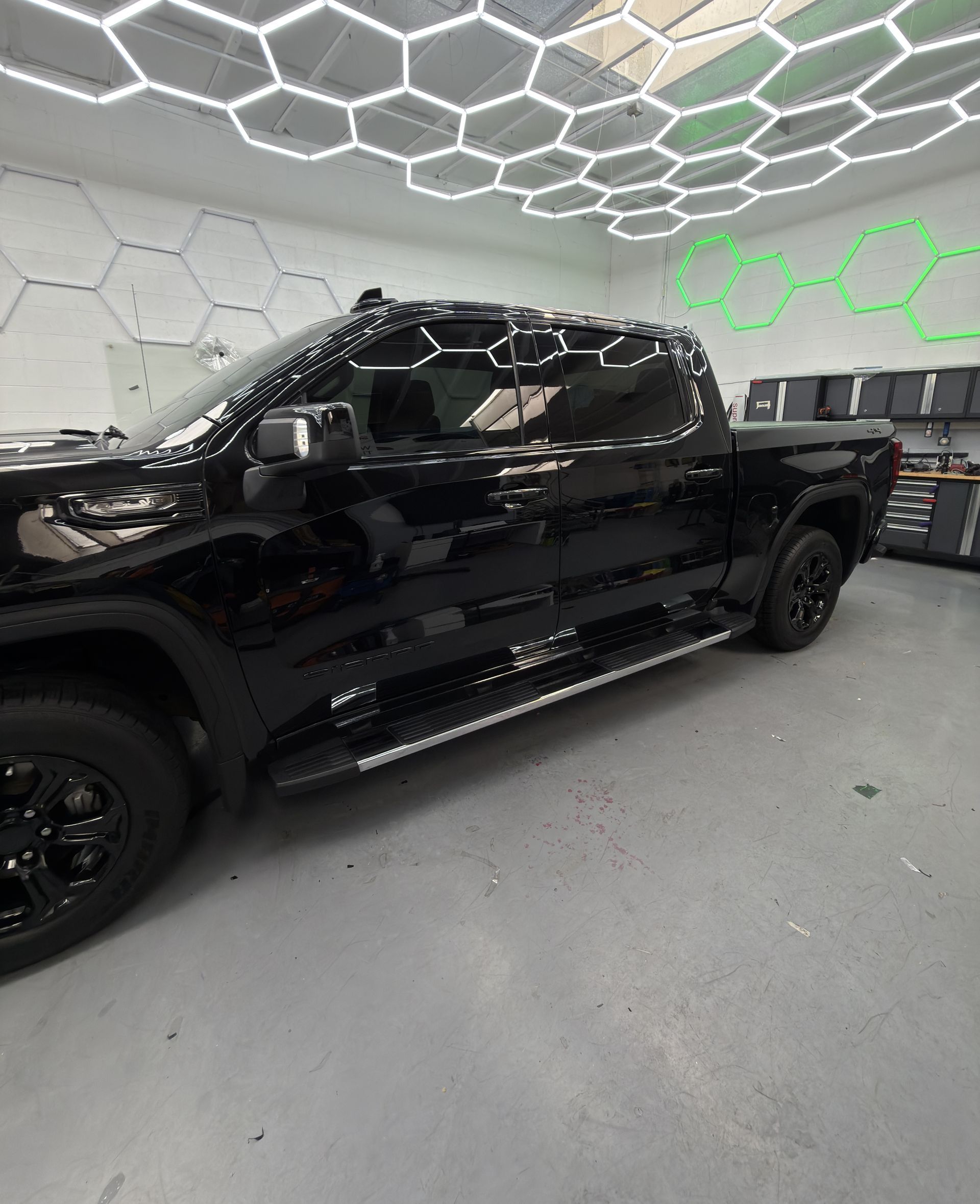 Black pickup truck in a modern garage under hexagonal ceiling lights