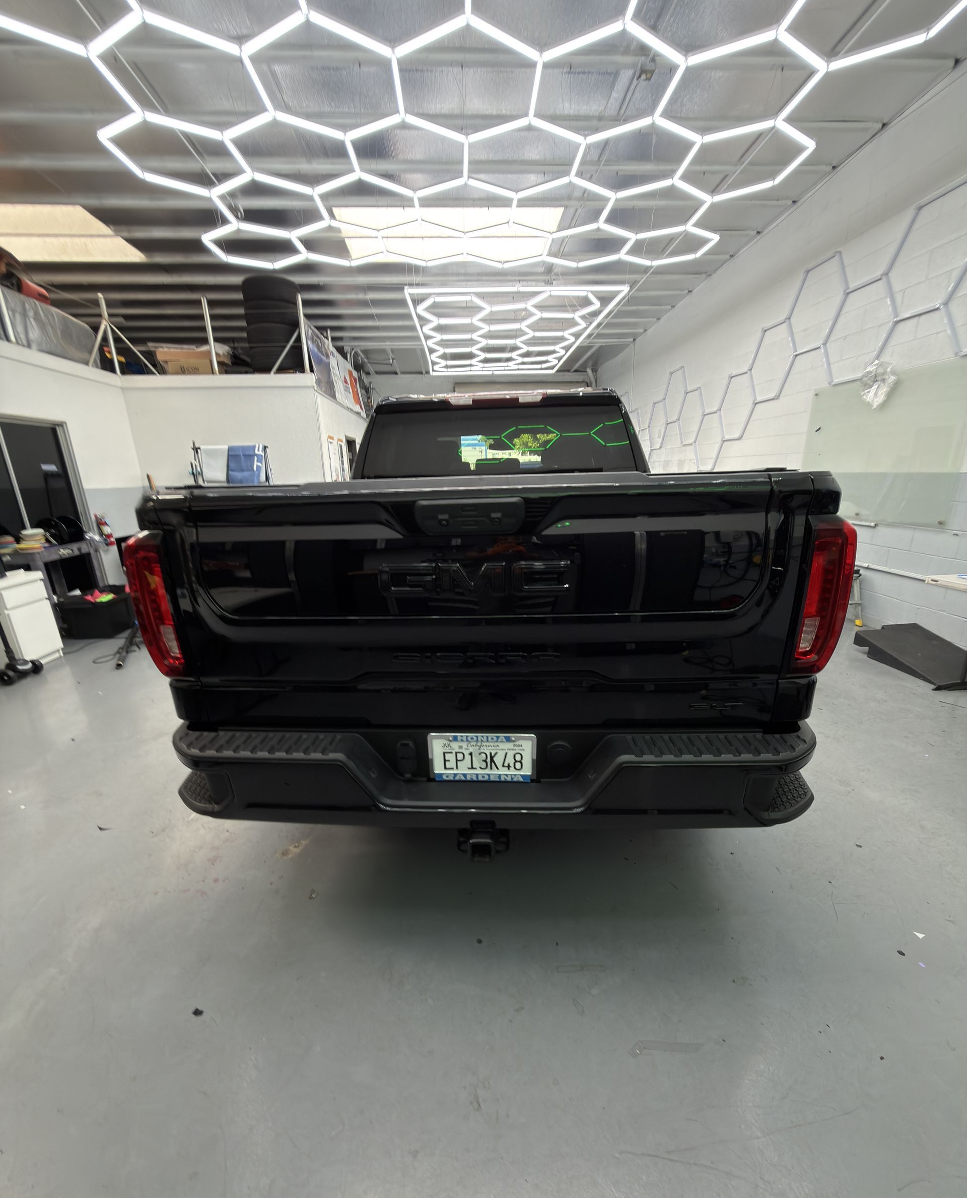 Black pickup truck rear view in a garage with hexagonal LED ceiling lights