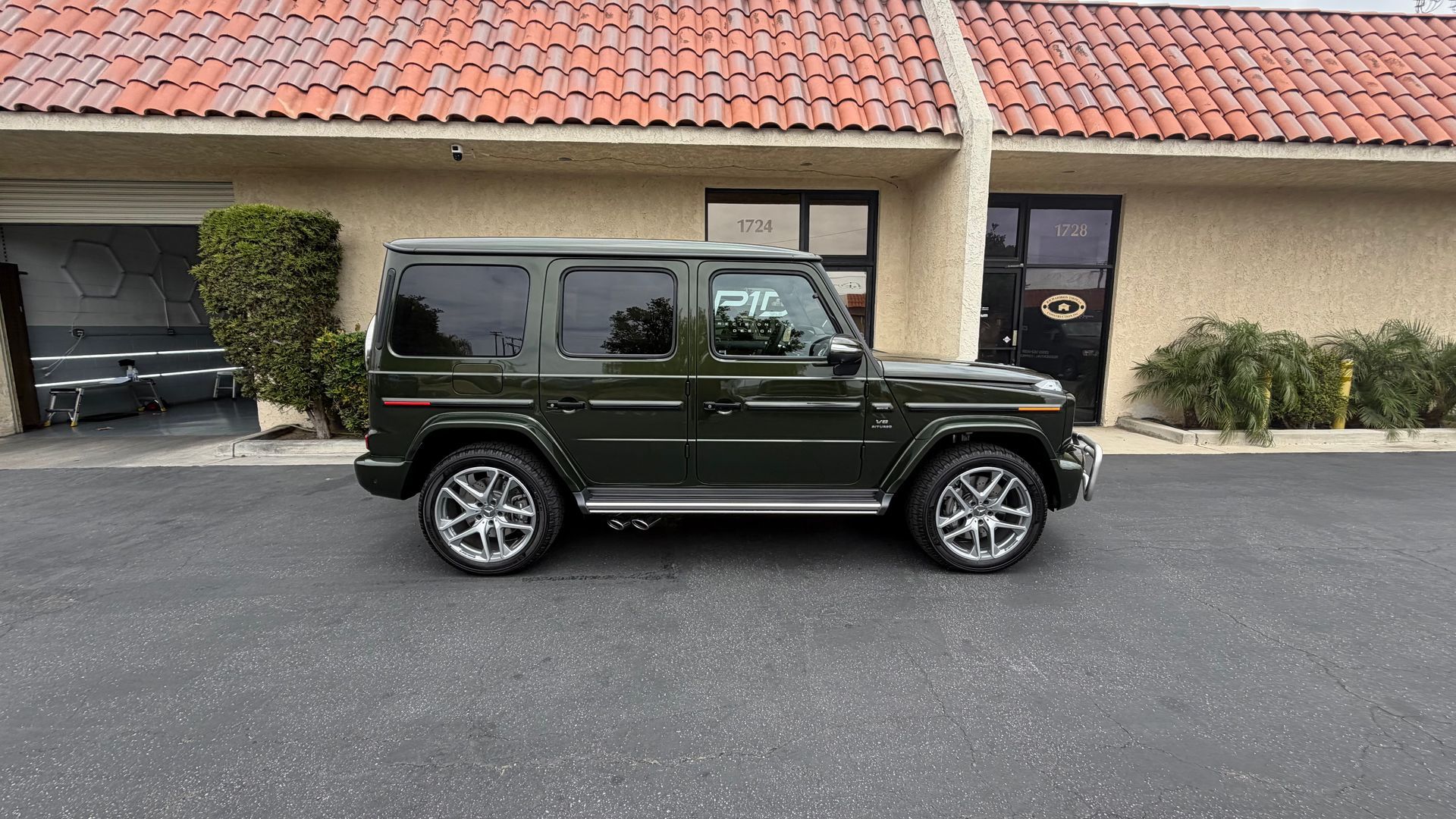 Dark green SUV parked in front of a building with a tiled roof and garage doors.