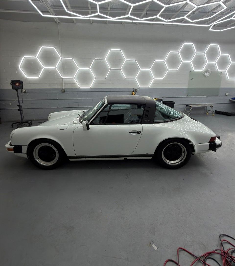 White classic Porsche 911 in a studio with geometric hexagon wall lights.