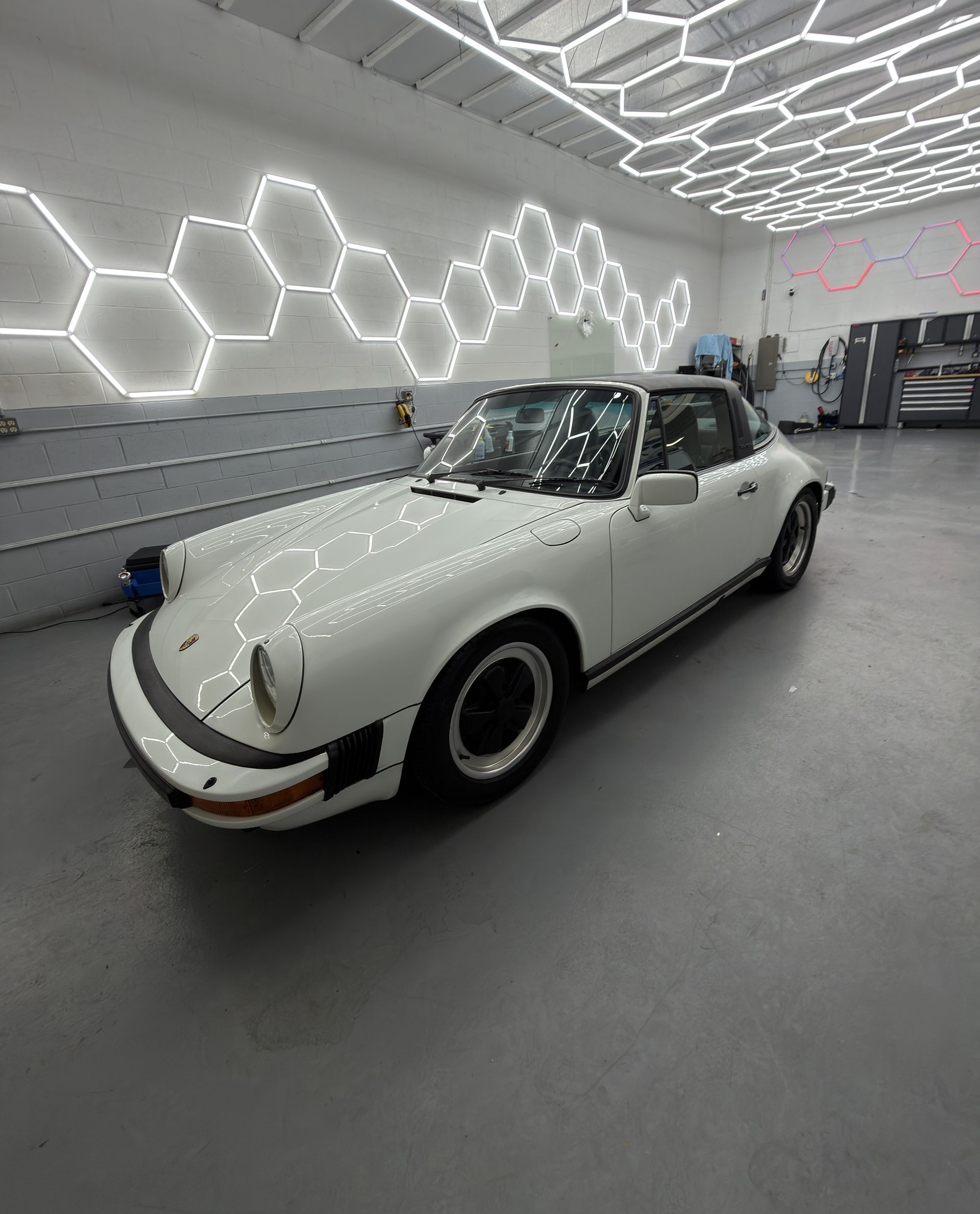 White classic Porsche 911 in a modern showroom with hexagonal wall lights