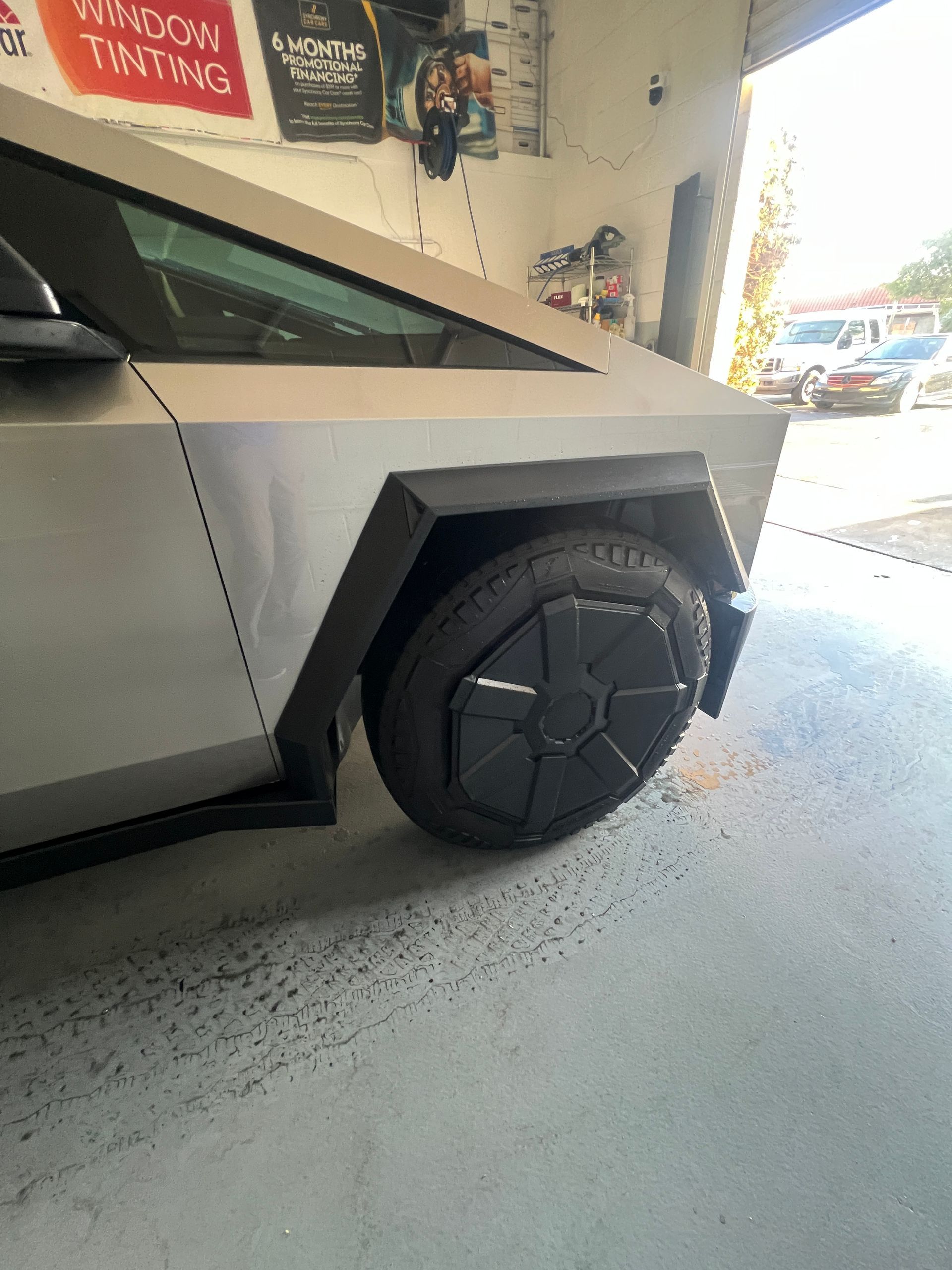 Silver angular pickup truck with black wheel in a garage, side view close-up