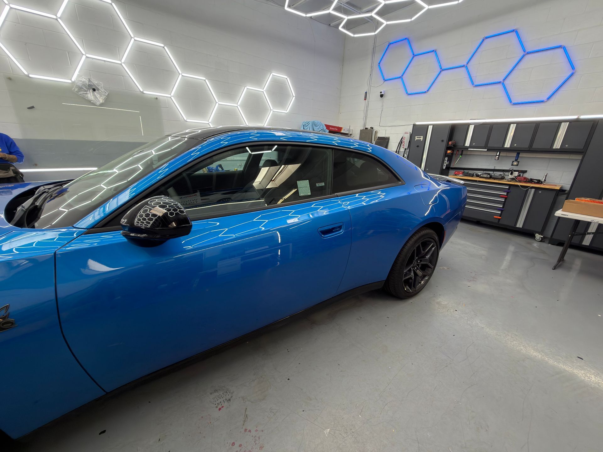 Blue sedan in a modern garage with hexagon wall lights and tool cabinets