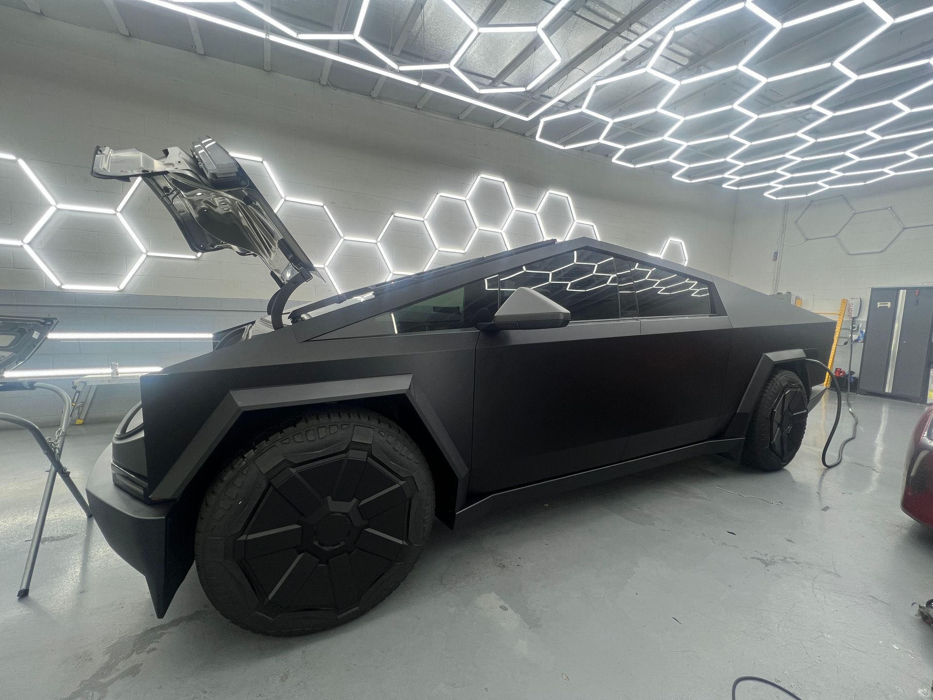 Matte black futuristic electric truck in a bright showroom with hexagonal ceiling lights