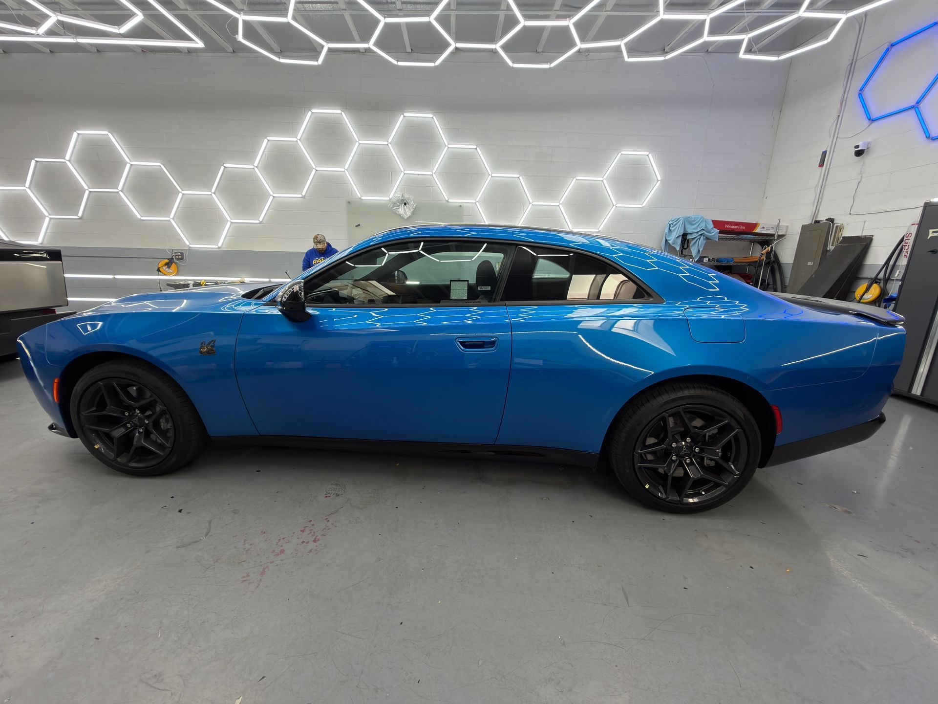 Blue sports coupe in a showroom with geometric wall lighting and a gray floor