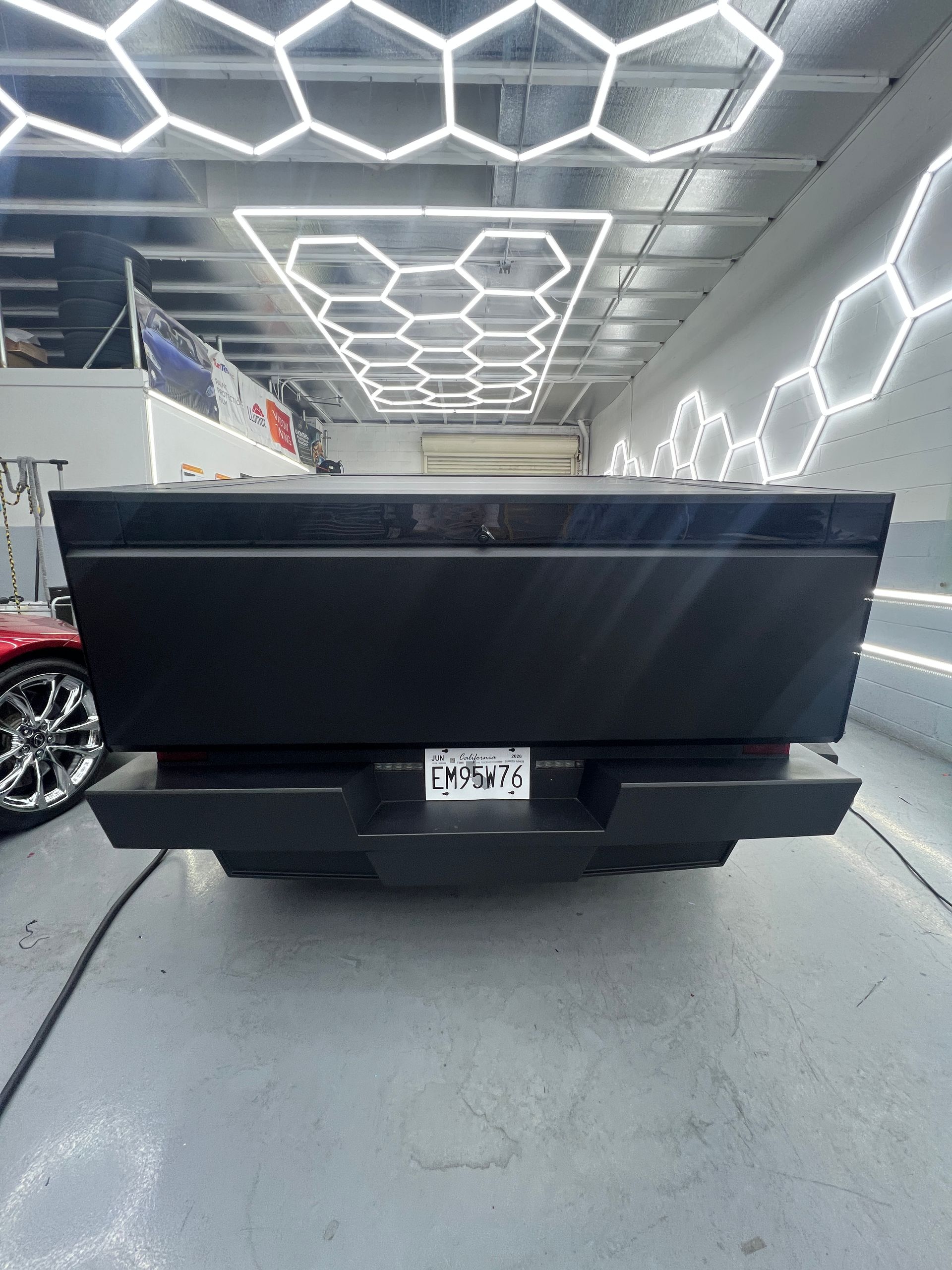 Black custom pickup truck parked in a modern showroom with hexagon ceiling lights