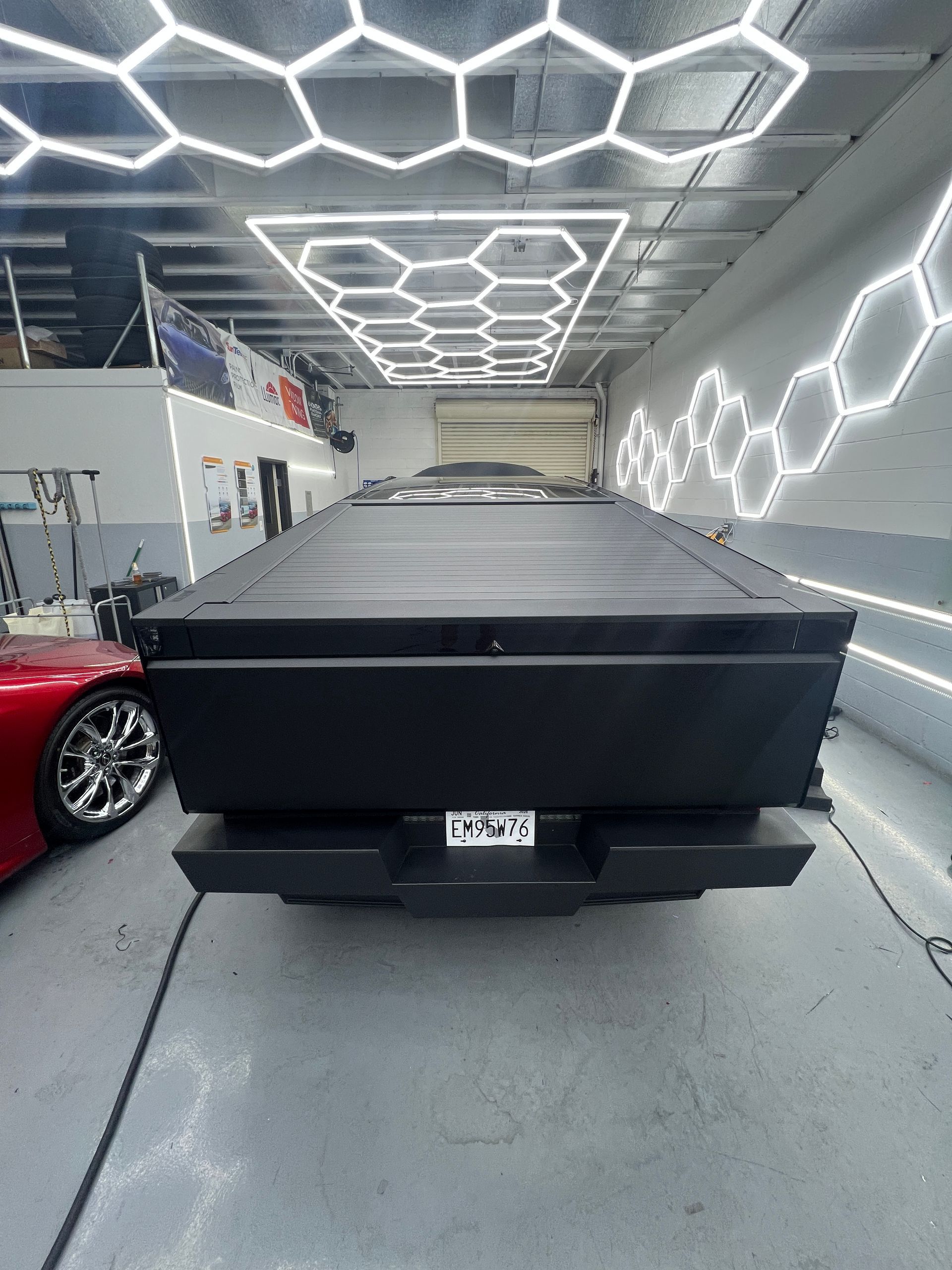 Black pickup truck in a neon-lit garage, viewed from the rear