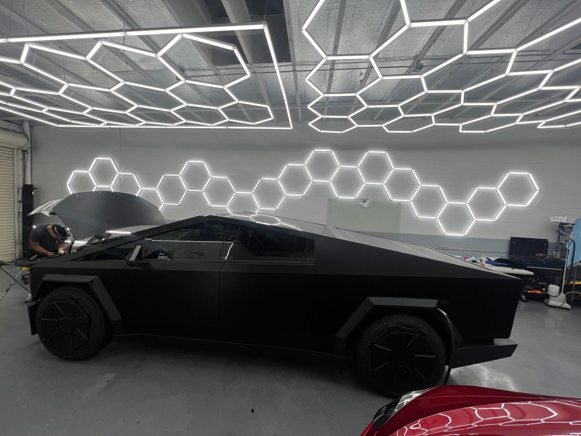 Matte black futuristic pickup in a garage with hexagonal LED wall lights