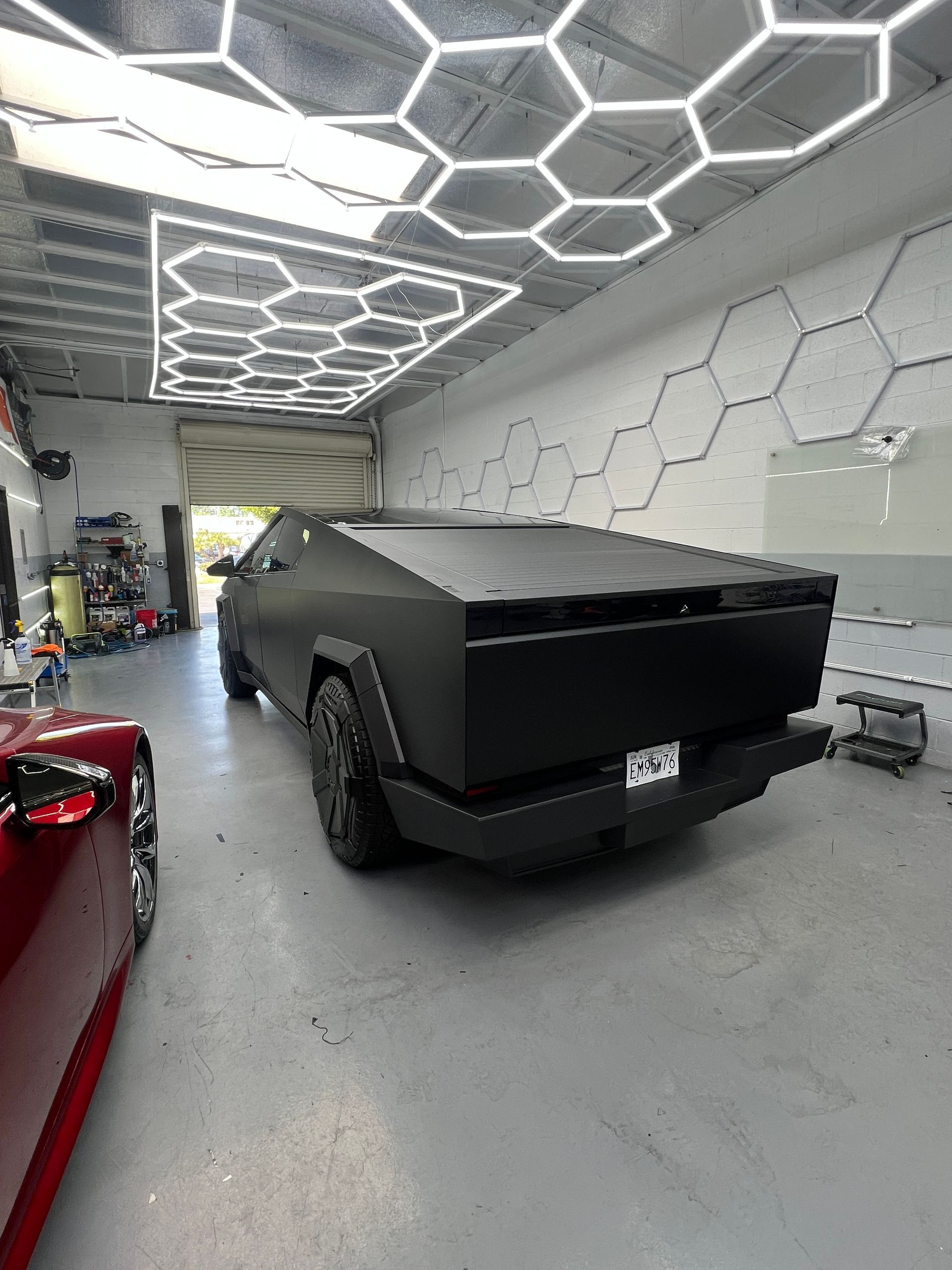 Black Cybertruck parked inside a modern garage with hexagonal ceiling lights