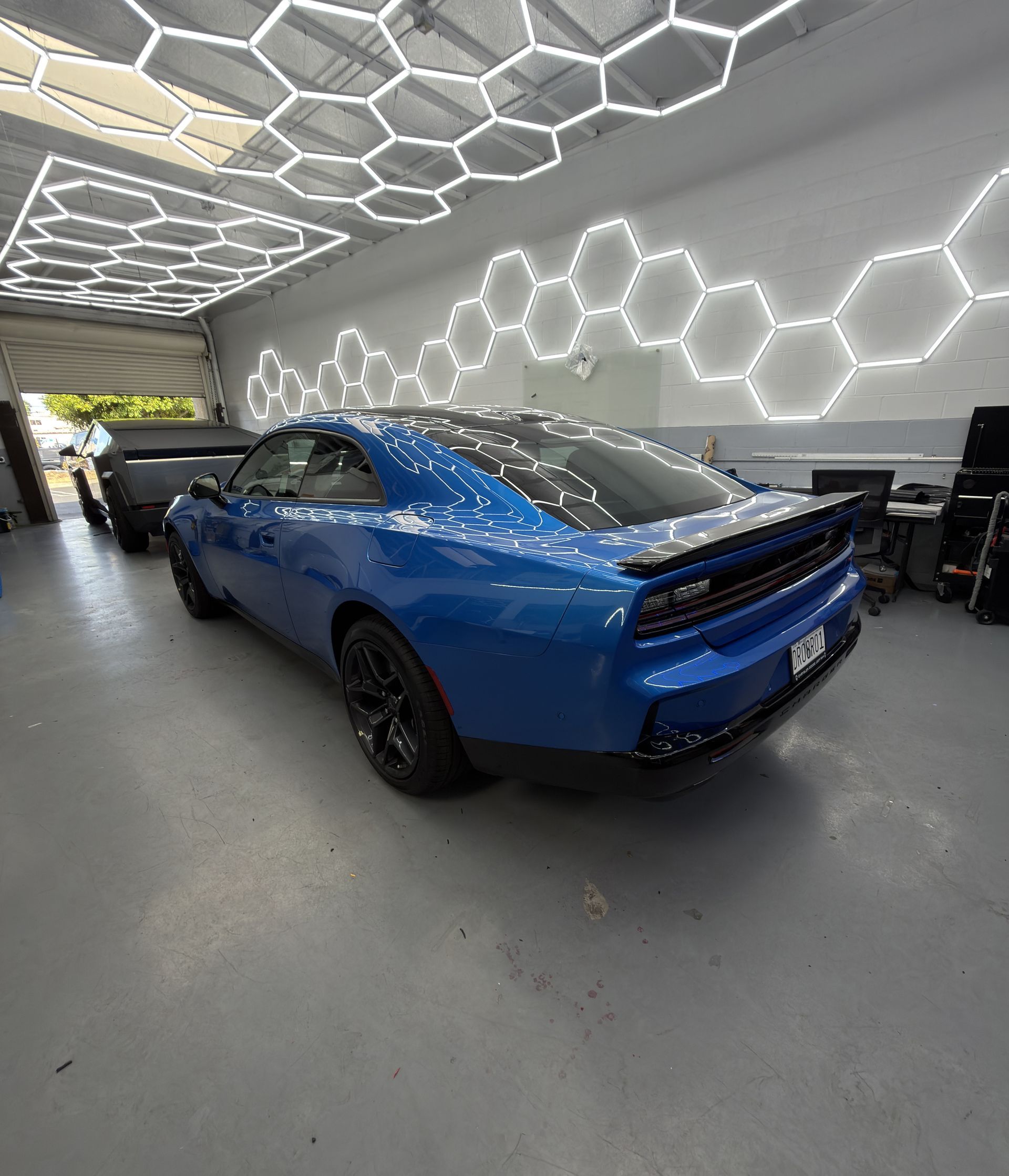 Blue sports car in a modern showroom with hexagonal ceiling lights and illuminated wall panels