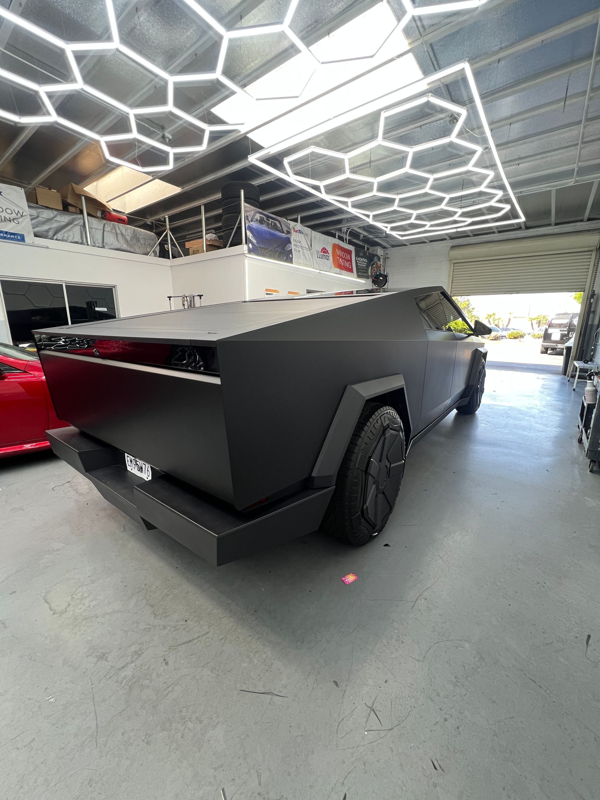 Matte black angular pickup truck in a showroom with hexagon ceiling lights.