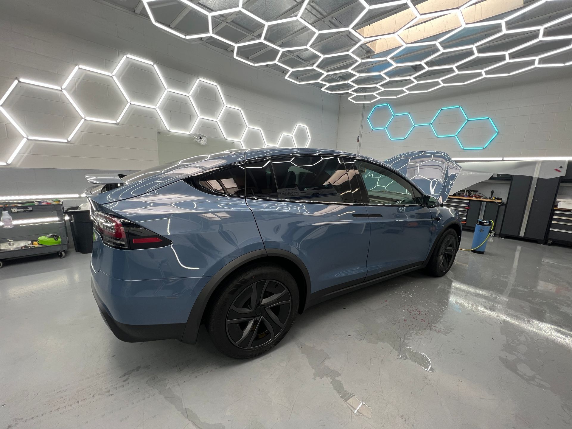 Blue Tesla in a modern showroom with hexagonal ceiling lights
