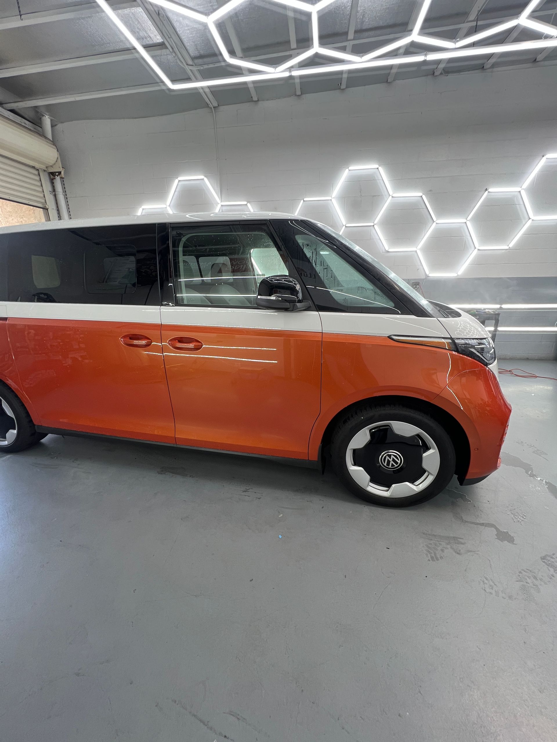 Orange and black compact van parked indoors under hexagonal wall lights