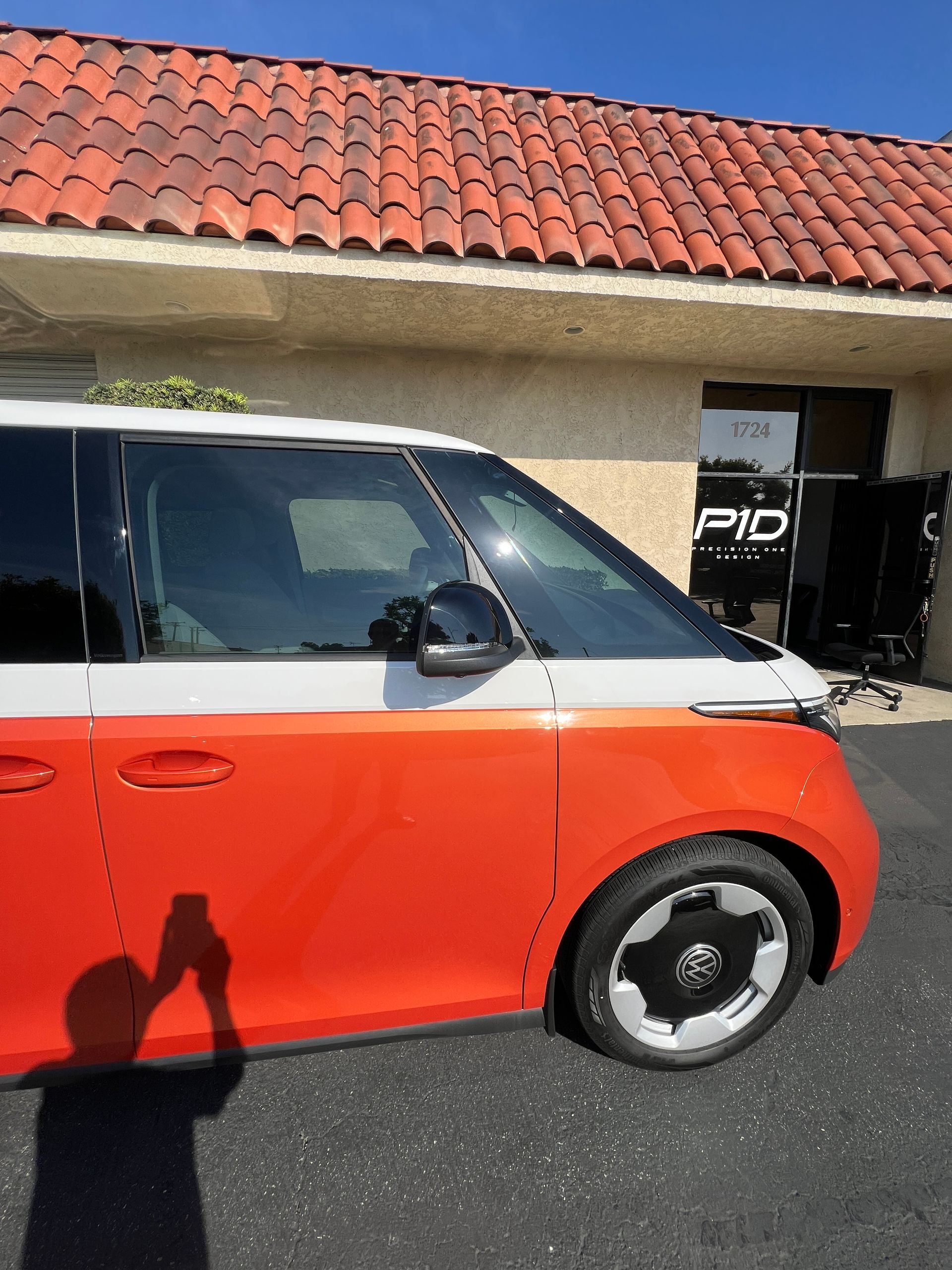 Orange and white compact car parked outside a building with a red tile roof