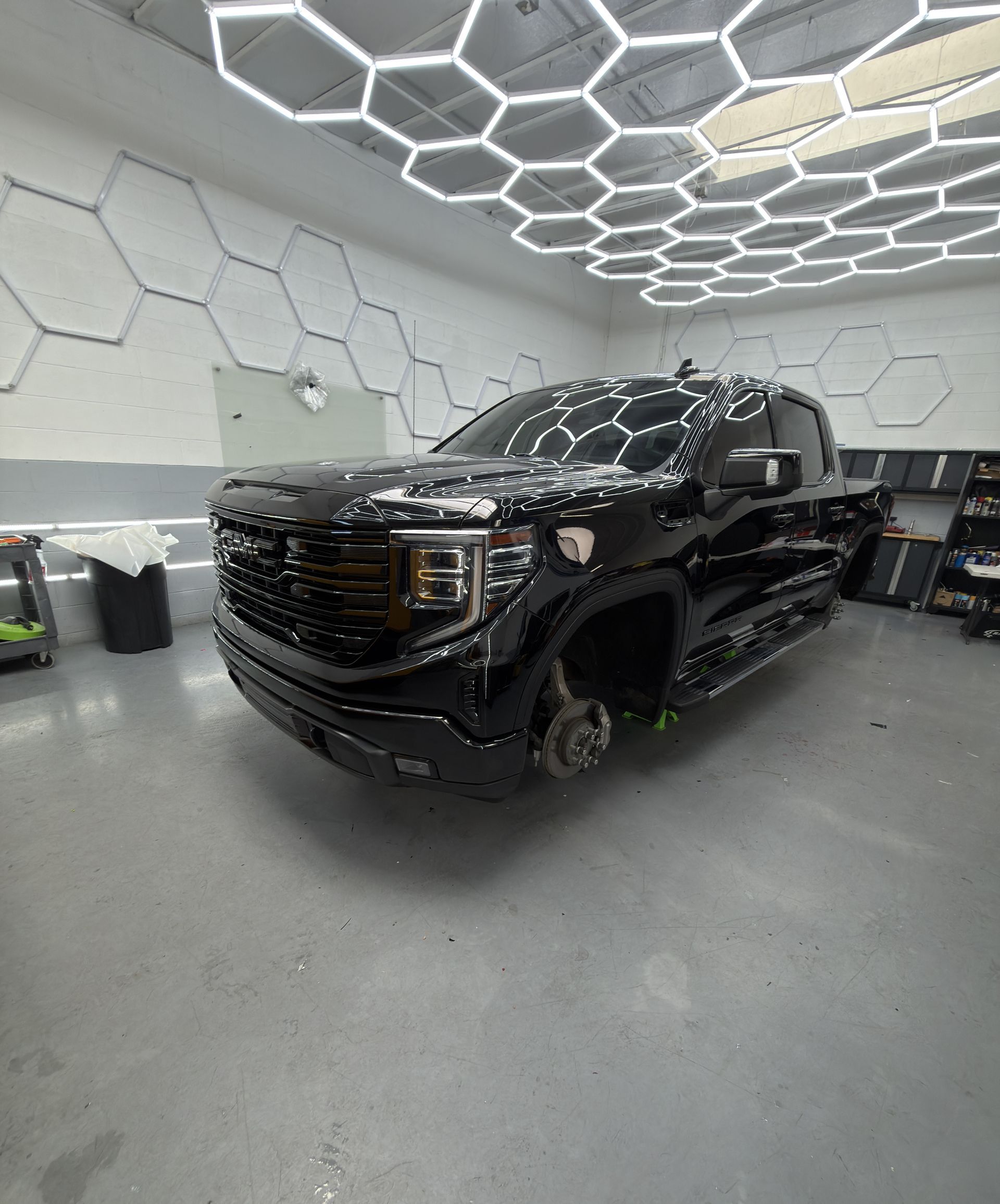 Black GMC pickup truck in a modern showroom with hexagonal ceiling lights