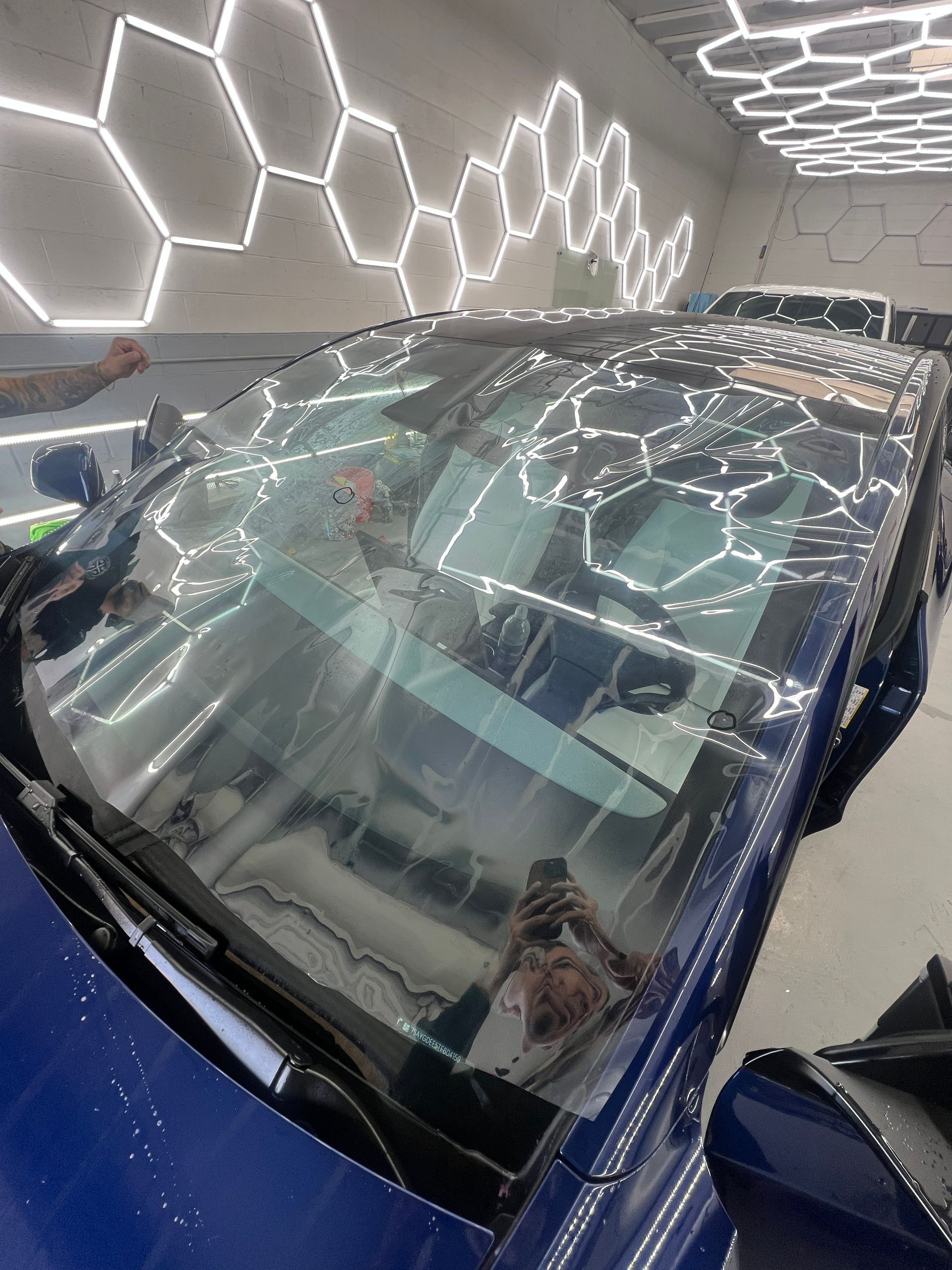 Blue car under hexagonal light reflections in a showroom-like setting
