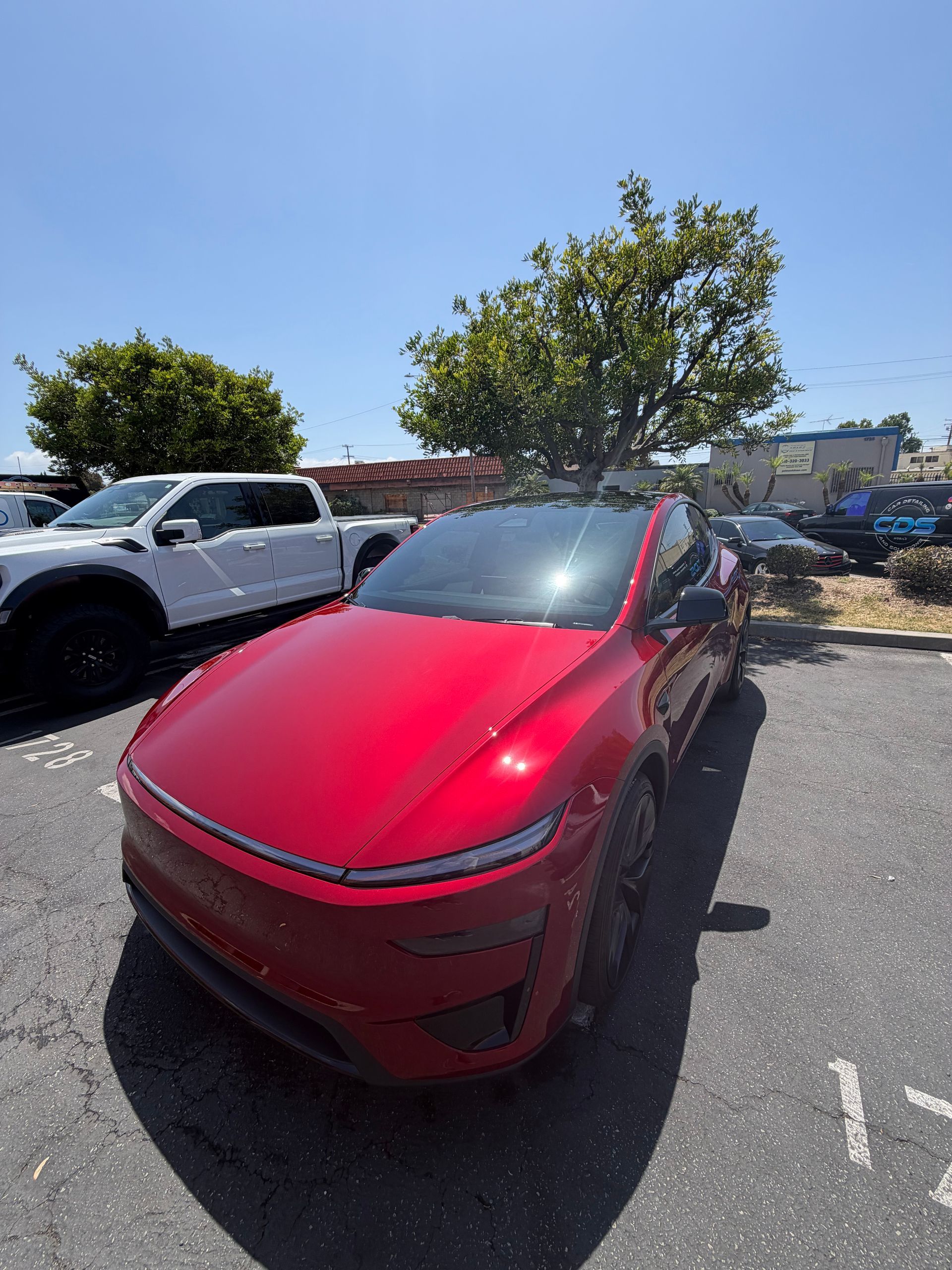 Red SUV parked in a sunny lot next to a white truck under a blue sky