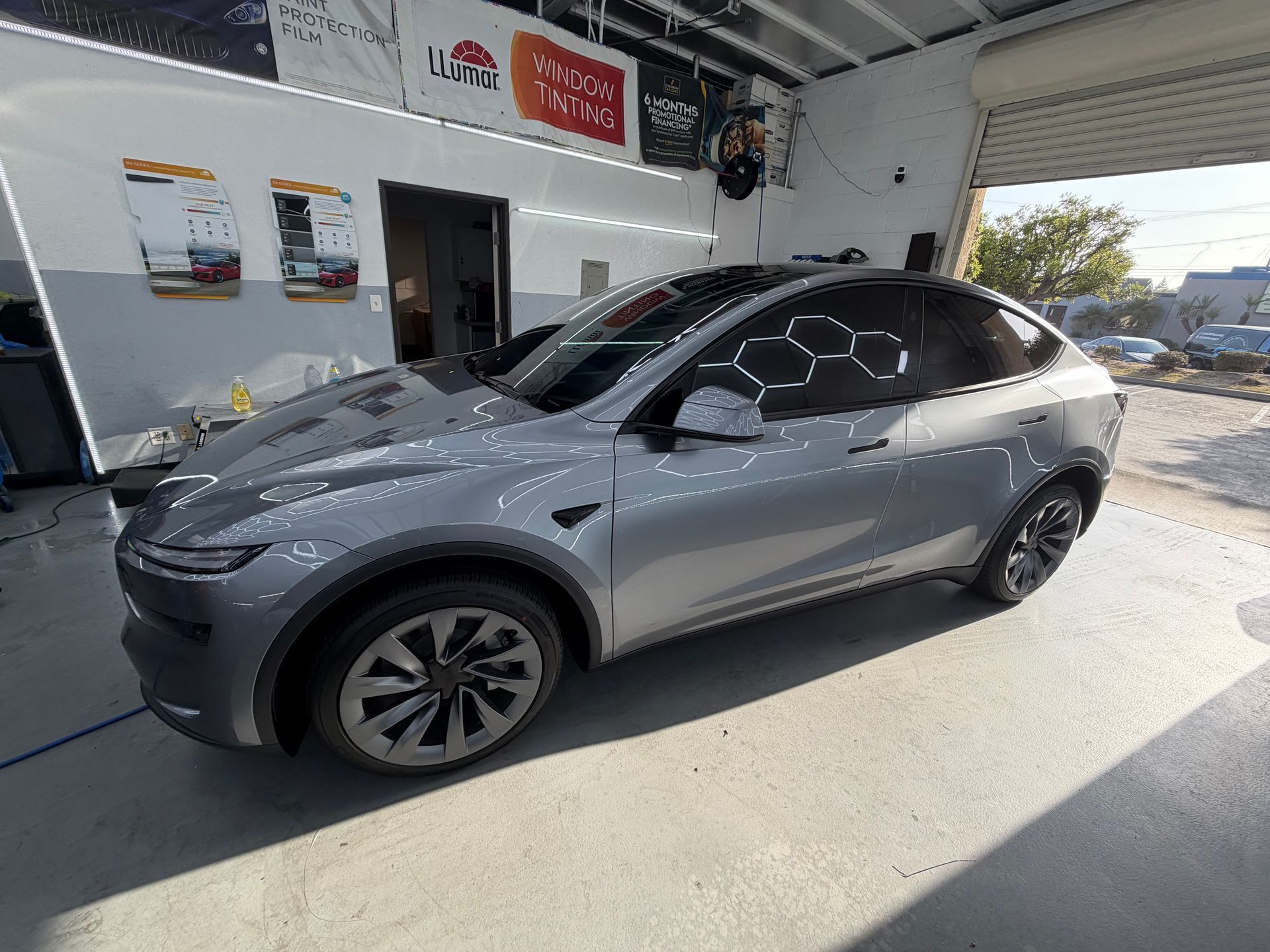 Gray Tesla parked in a service bay, viewed from the front-left side.