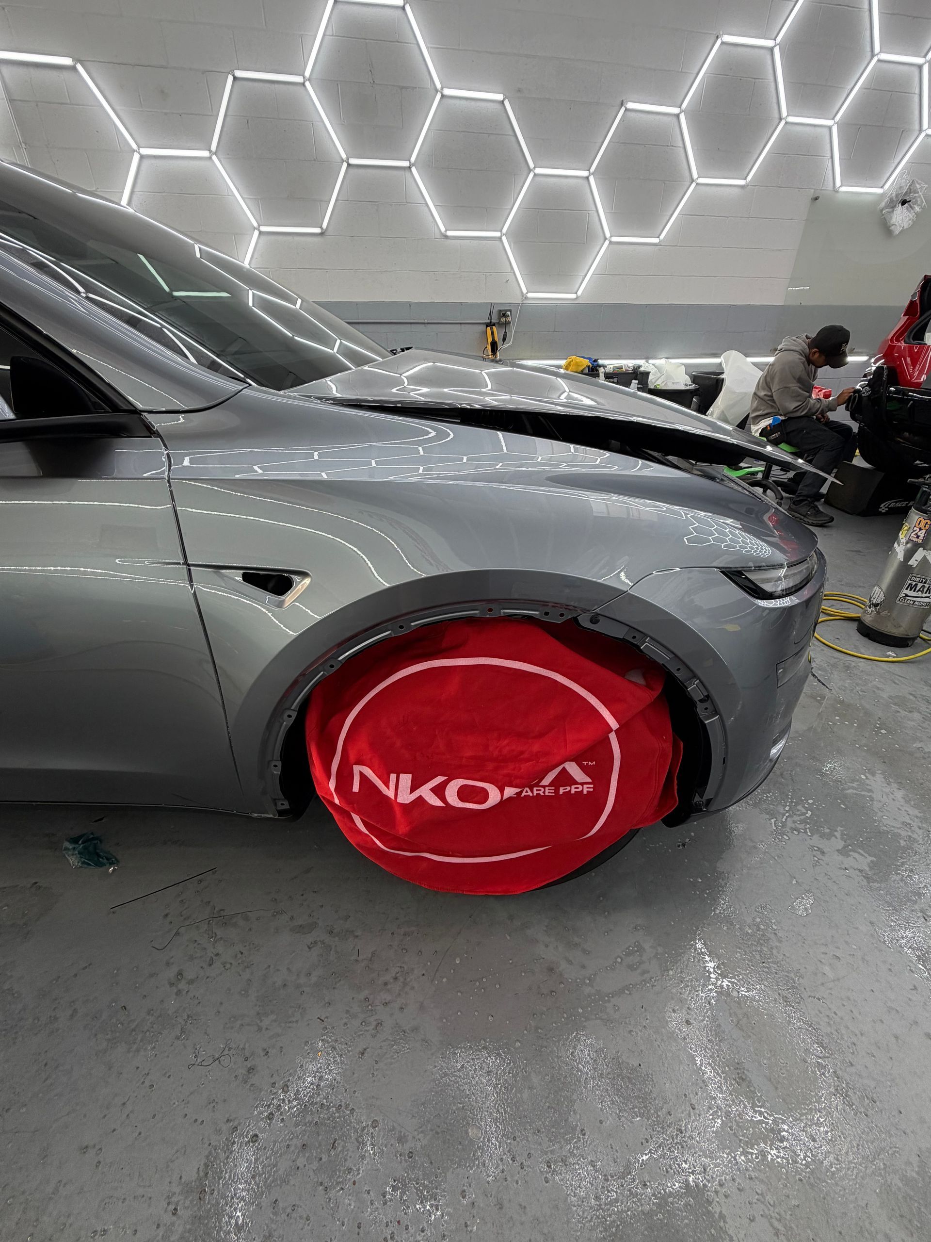 Gray car with red wheel cover in a showroom with hexagon ceiling lights
