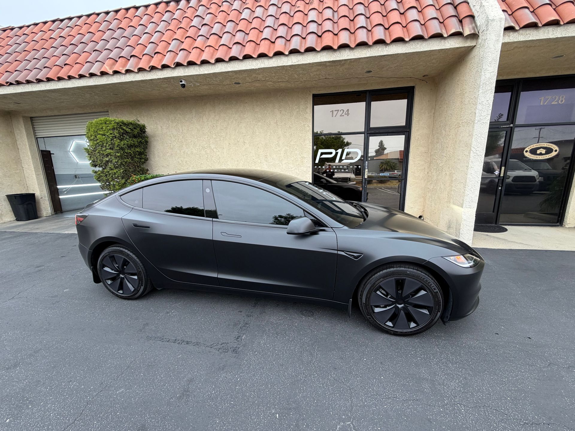 Black sedan parked outside a storefront with a tiled roof.