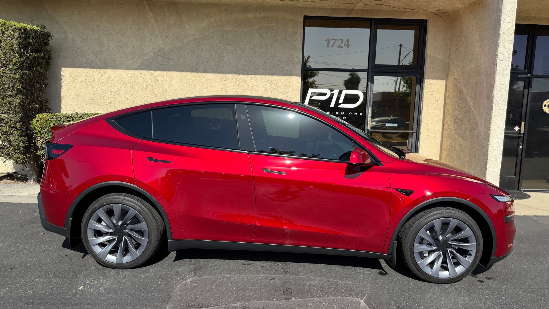 Red Tesla parked outside a building with a Pid sign in the window