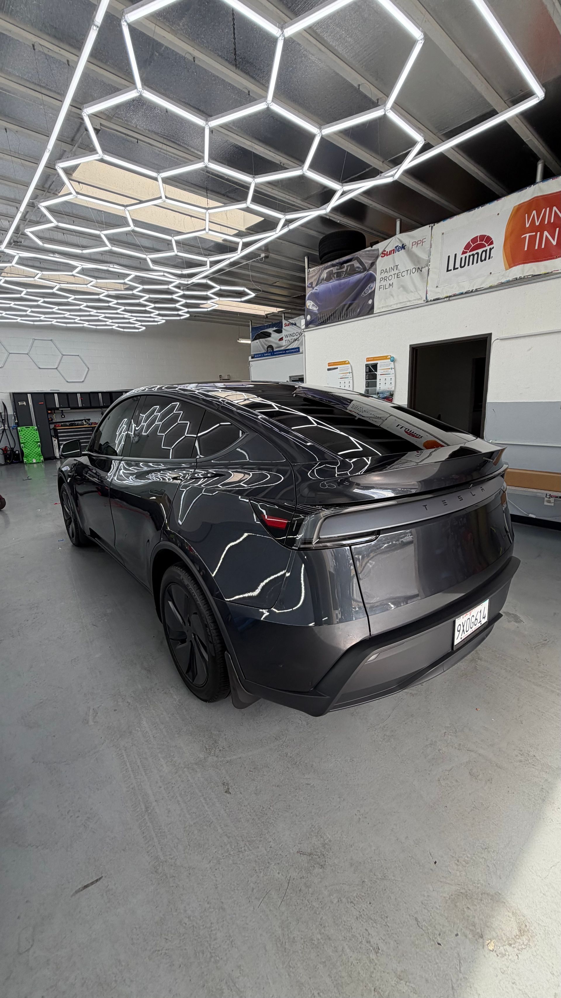 Dark gray sports sedan parked in a modern indoor showroom with geometric ceiling lights