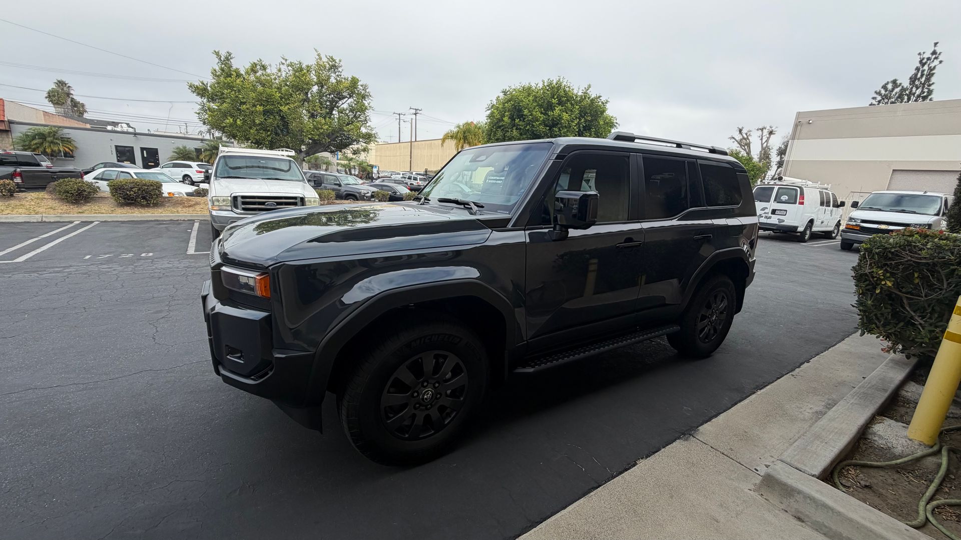 Black SUV parked in a parking lot near a curb and sidewalk on an overcast day