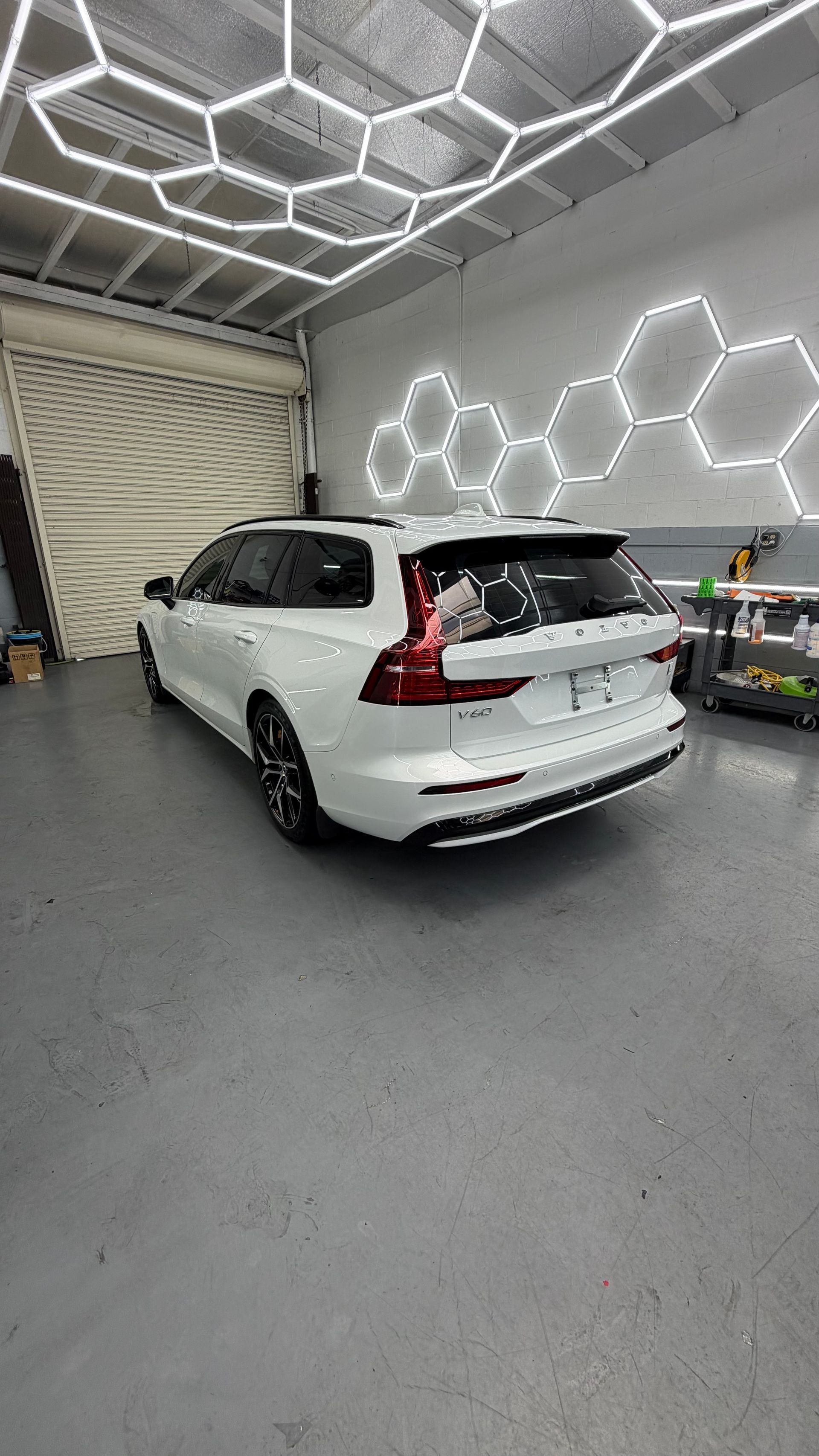 White SUV parked inside a modern garage with hexagonal ceiling and wall lights