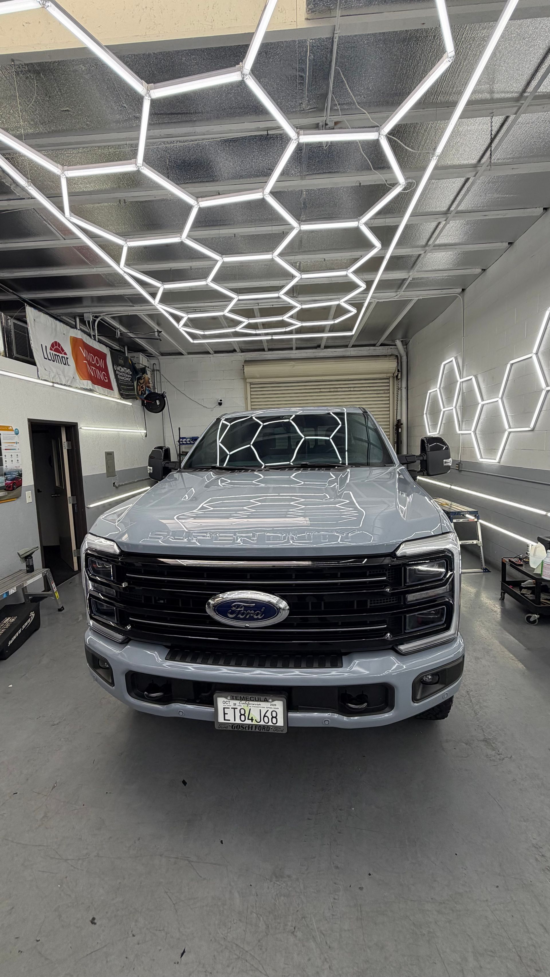 Silver Ford SUV parked inside a workshop with hexagonal LED ceiling lights.