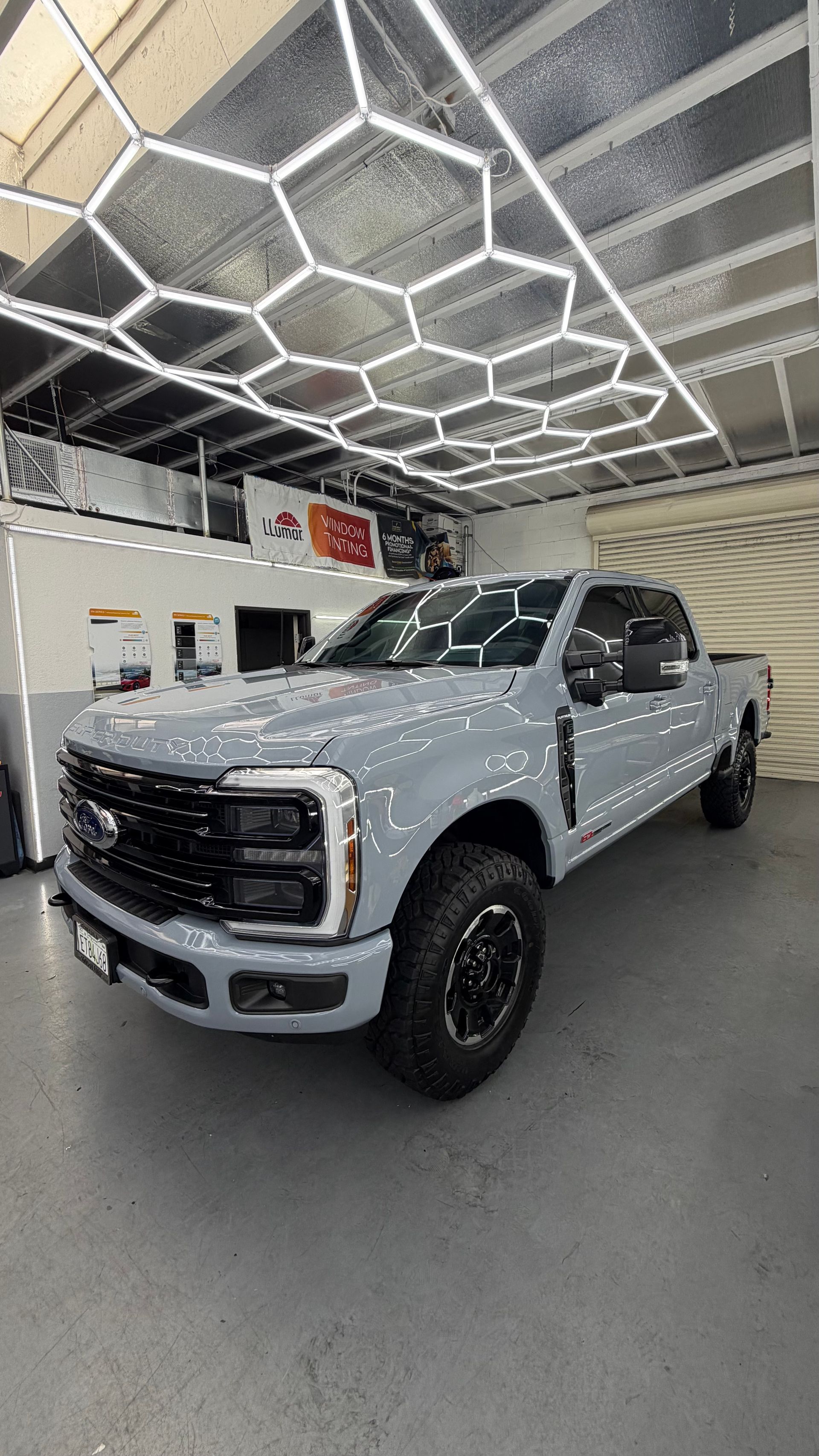 White lifted pickup truck inside a showroom under geometric ceiling lights