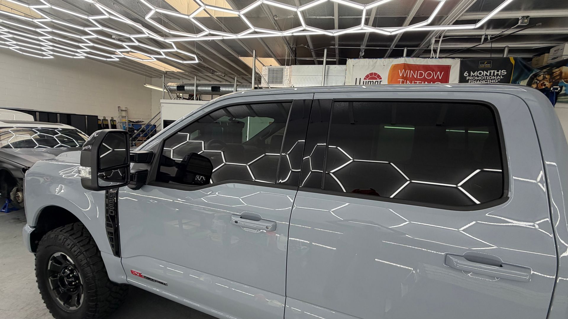 White pickup truck in a showroom under bright geometric ceiling lights