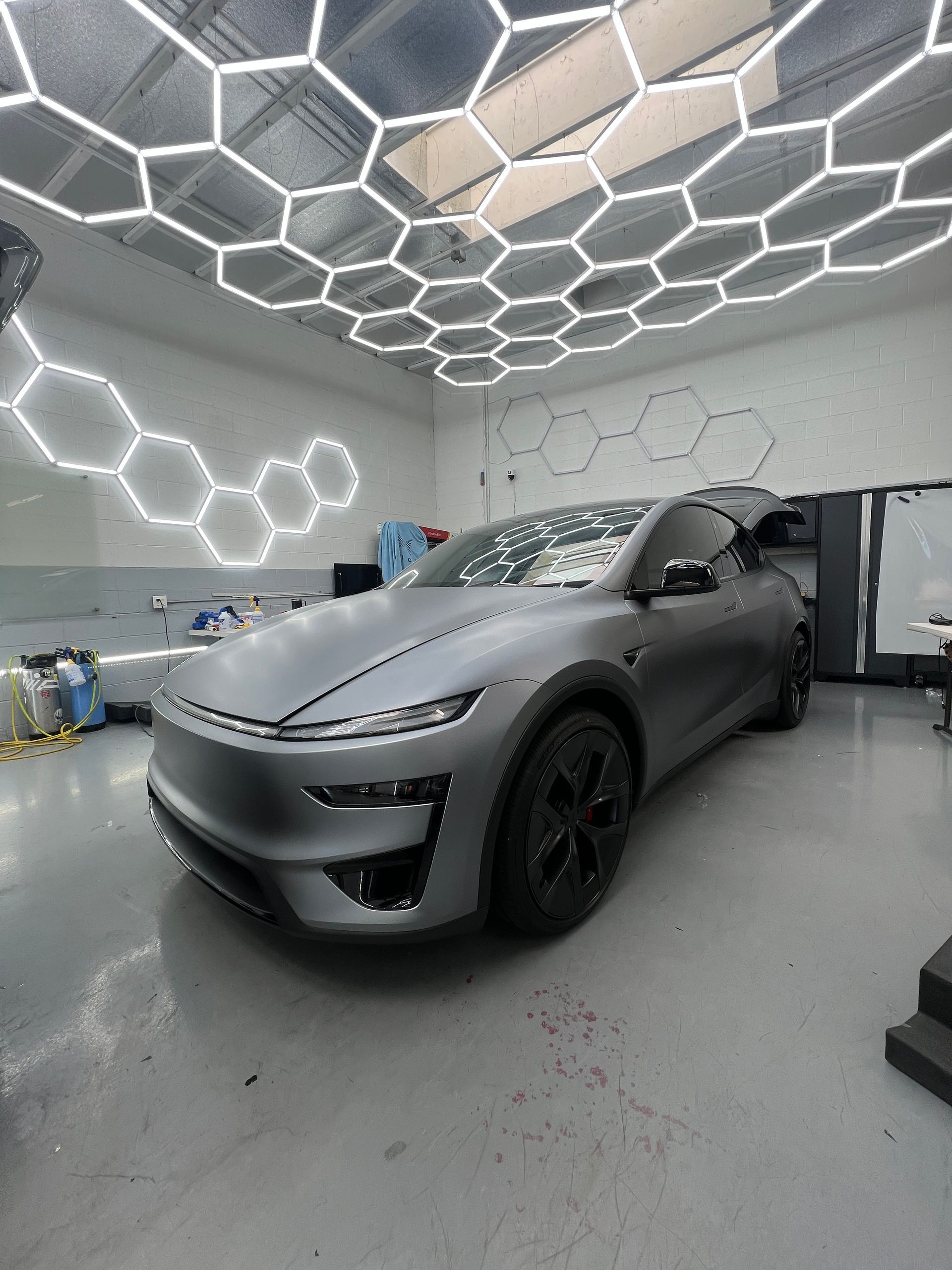 Matte gray sports car in a modern garage with hexagonal ceiling lights