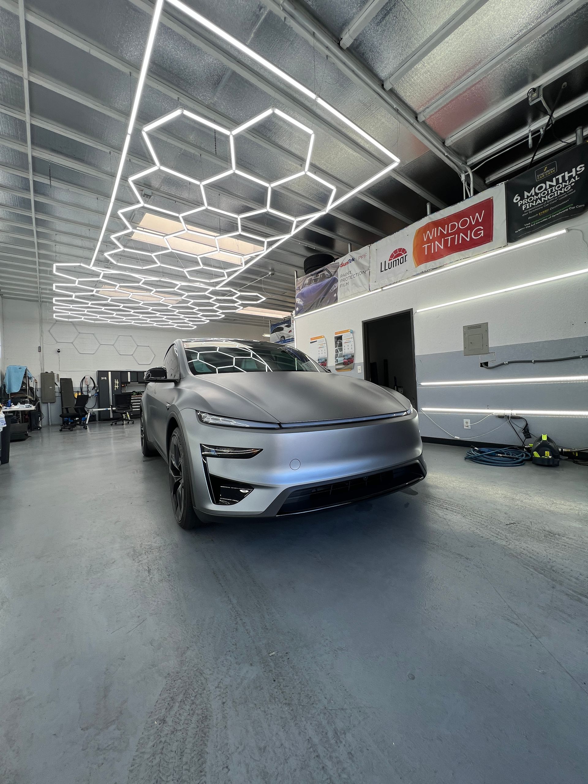 Silver futuristic concept car in a sleek showroom with geometric ceiling lights
