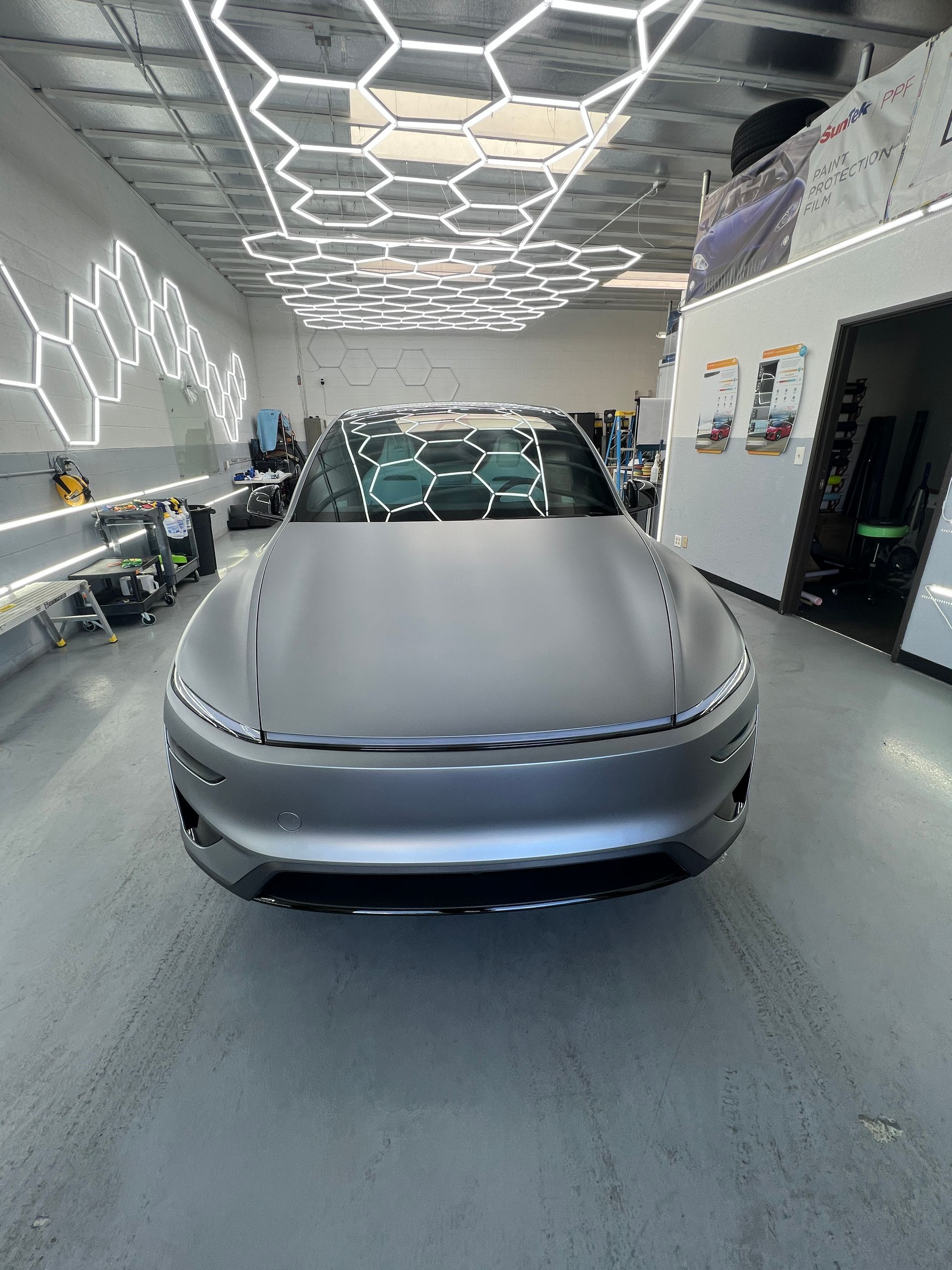 Silver concept car in a futuristic showroom with hexagonal ceiling lights and wall patterns