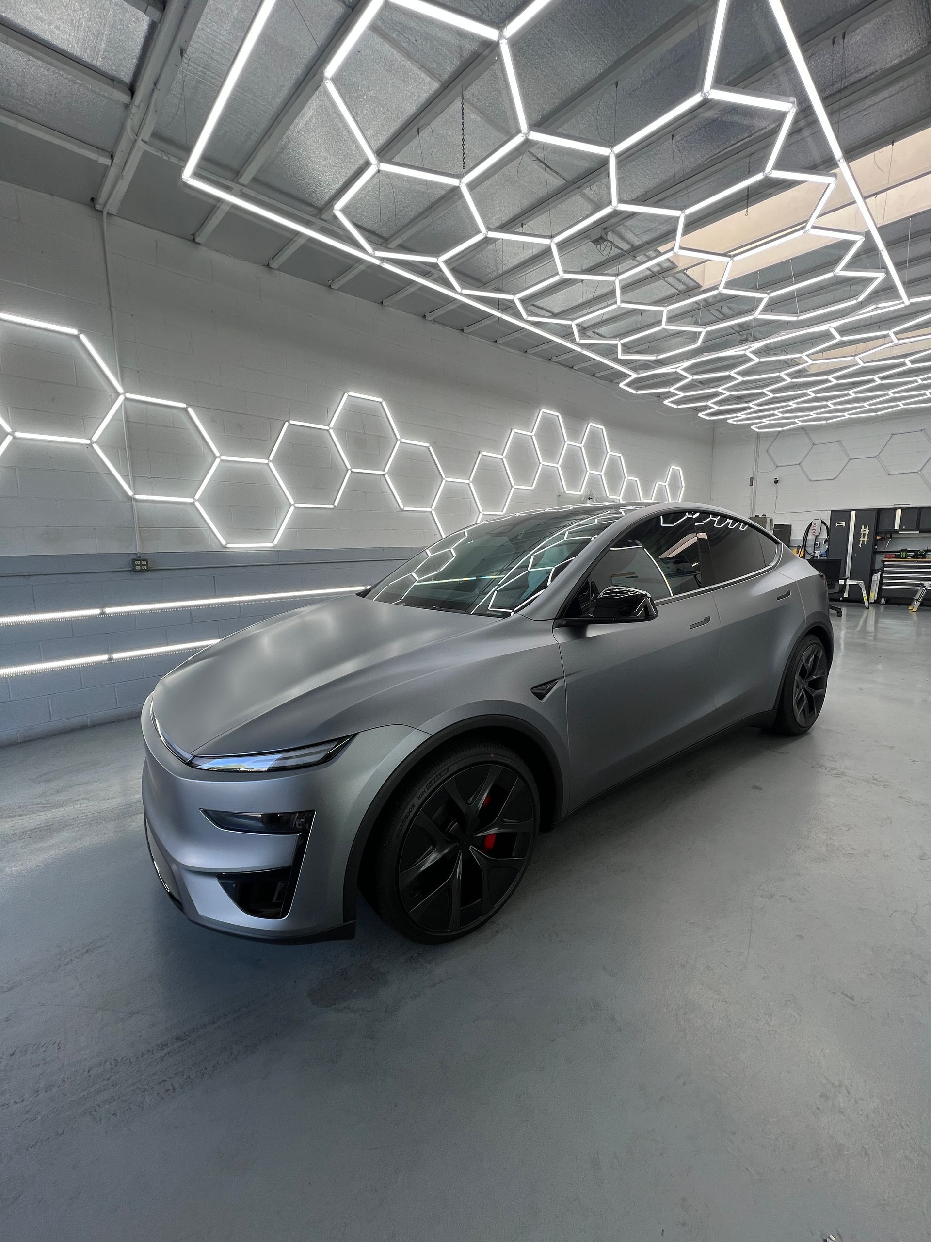 Matte gray sports car in a modern showroom with hexagonal LED ceiling lights