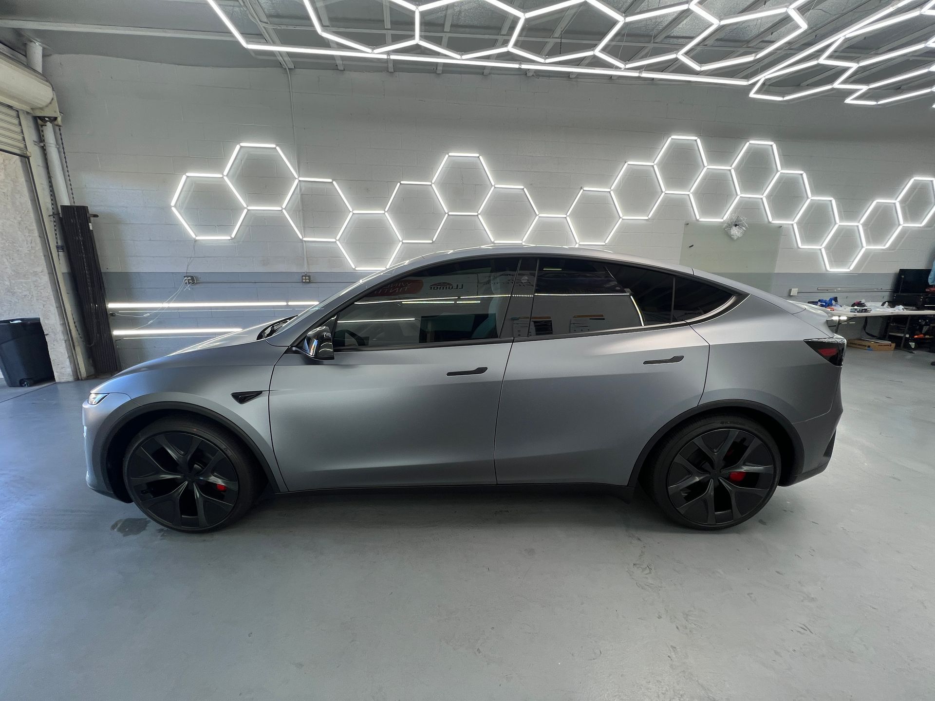 Gray Tesla sedan in a garage with illuminated hexagon wall lights