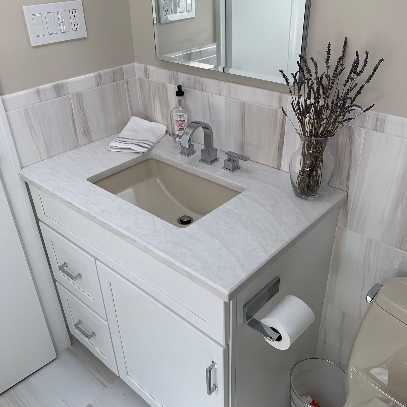 Bathroom vanity with a white cabinet, light-colored countertop, and a vessel sink.