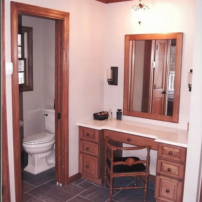 Bathroom with vanity, toilet in separate room, brown wood trim, and gray tile floor.