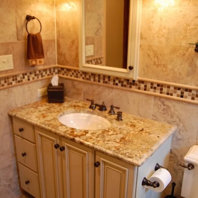 Bathroom with light beige vanity, granite countertop, oval sink, and mirror. Beige tile walls with mosaic border.