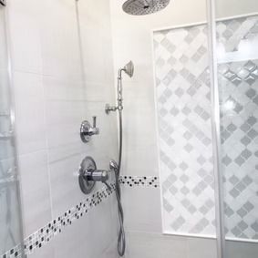 White tiled shower with silver fixtures, including a handheld shower and a rainfall showerhead.
