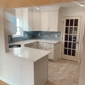 Modern white kitchen with a peninsula and glass-paneled door.