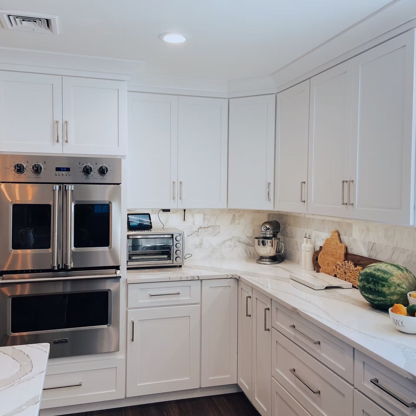 White kitchen cabinets and appliances with marble countertops.