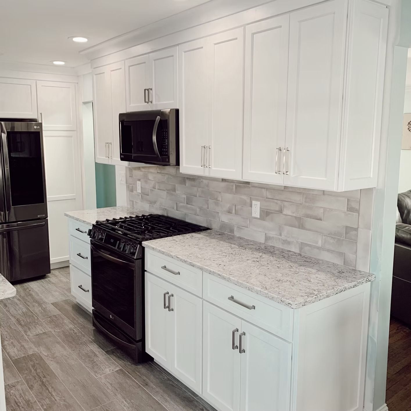 White kitchen with black appliances, gray countertops, and subway tile backsplash.