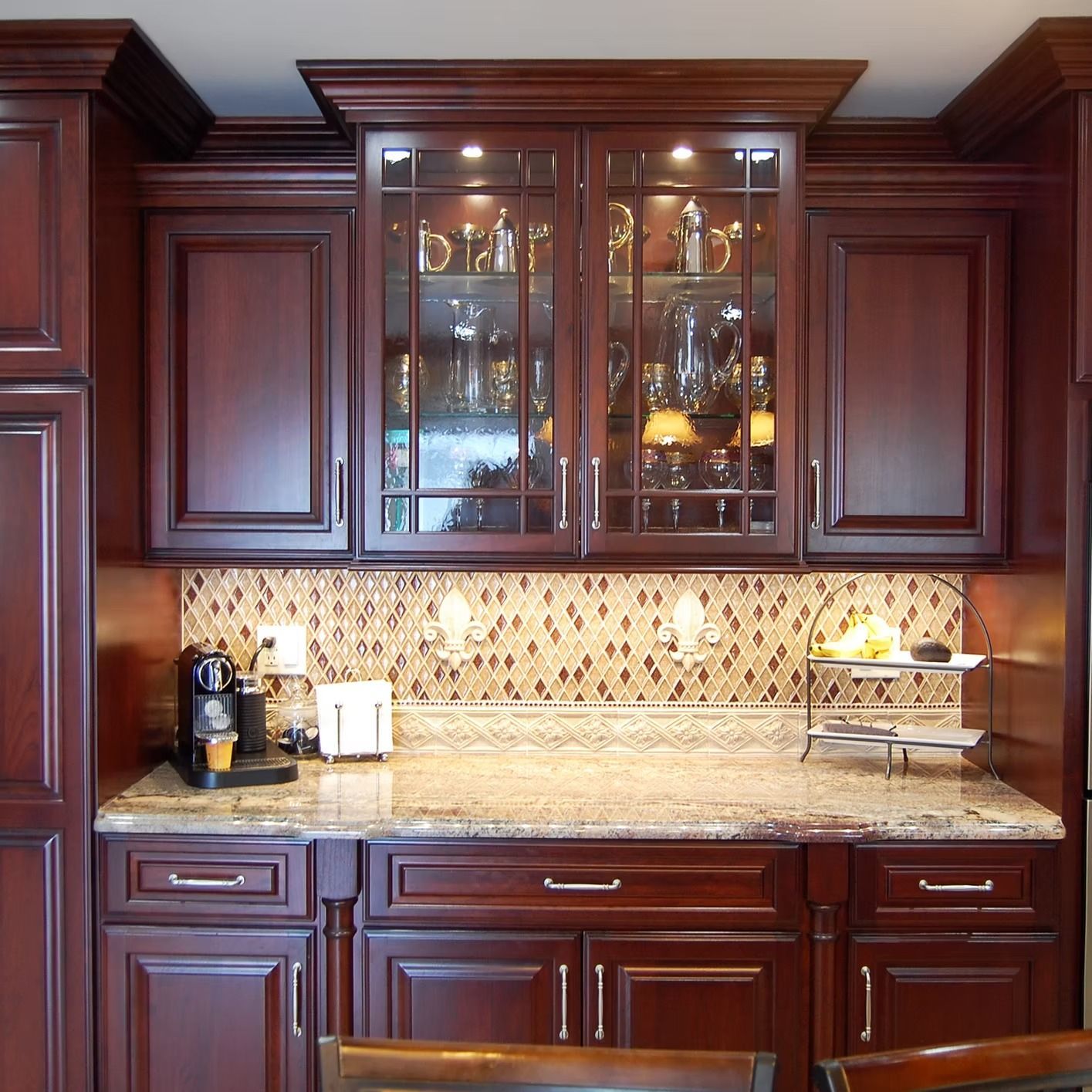 Dark wood kitchen cabinets with glass-front display cabinet, granite countertop, and mosaic backsplash.