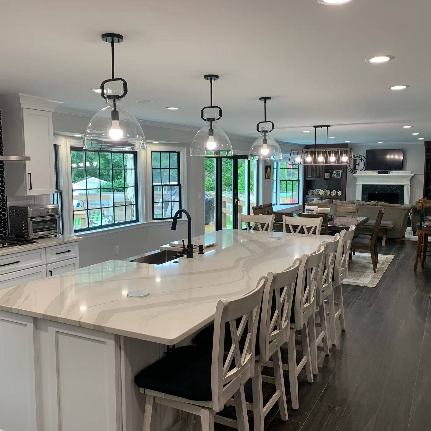 Spacious kitchen with a large island, pendant lights, and bar stools; opens to a living area.