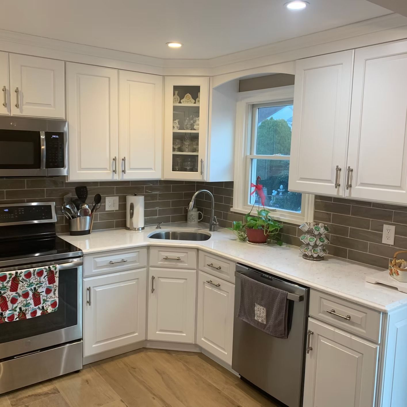 White kitchen with stainless steel appliances, white cabinets, and gray backsplash.